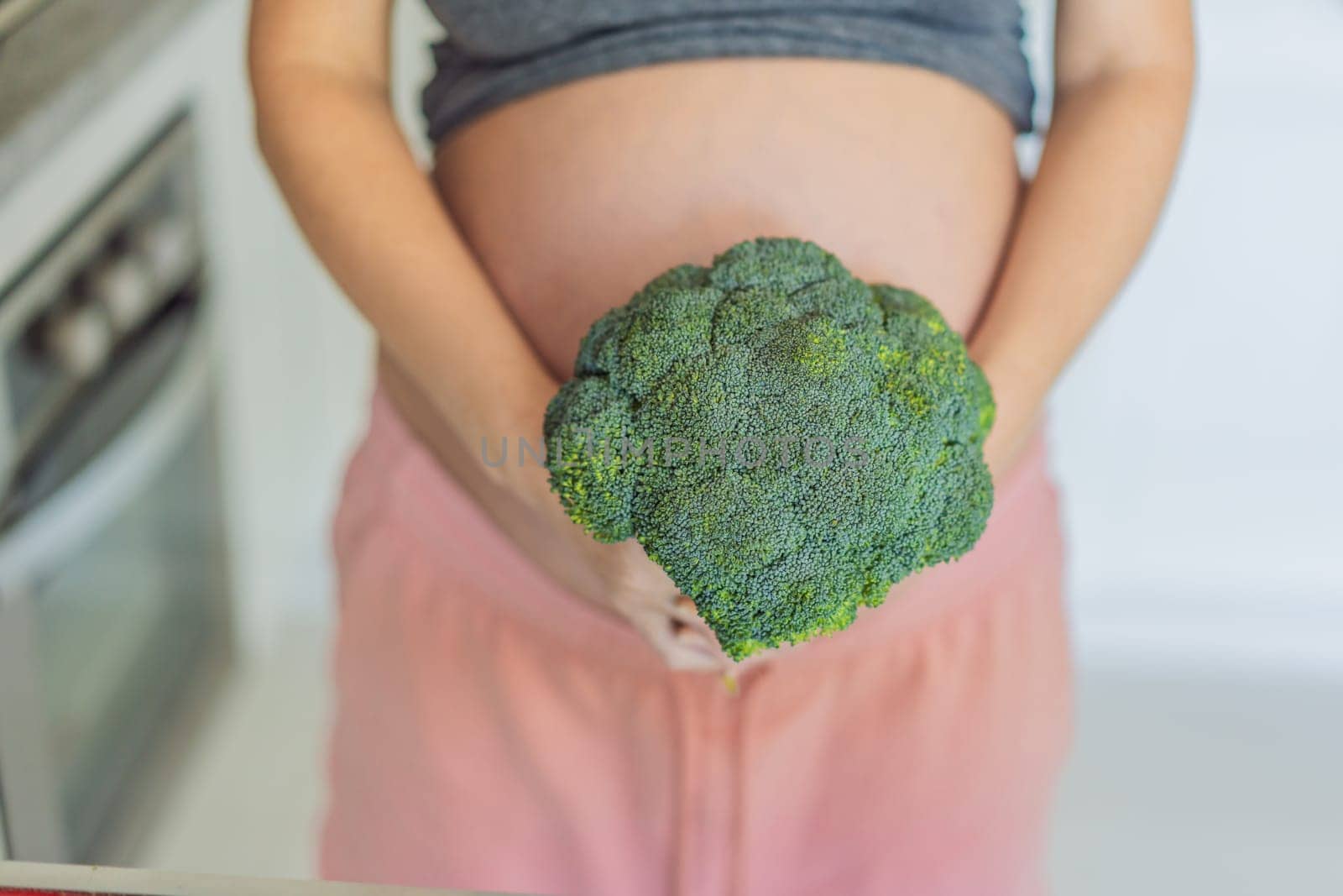 Embracing a nutrient-rich choice, a pregnant woman eagerly prepares to enjoy a wholesome serving of broccoli, prioritizing healthy and nourishing options during her pregnancy by galitskaya