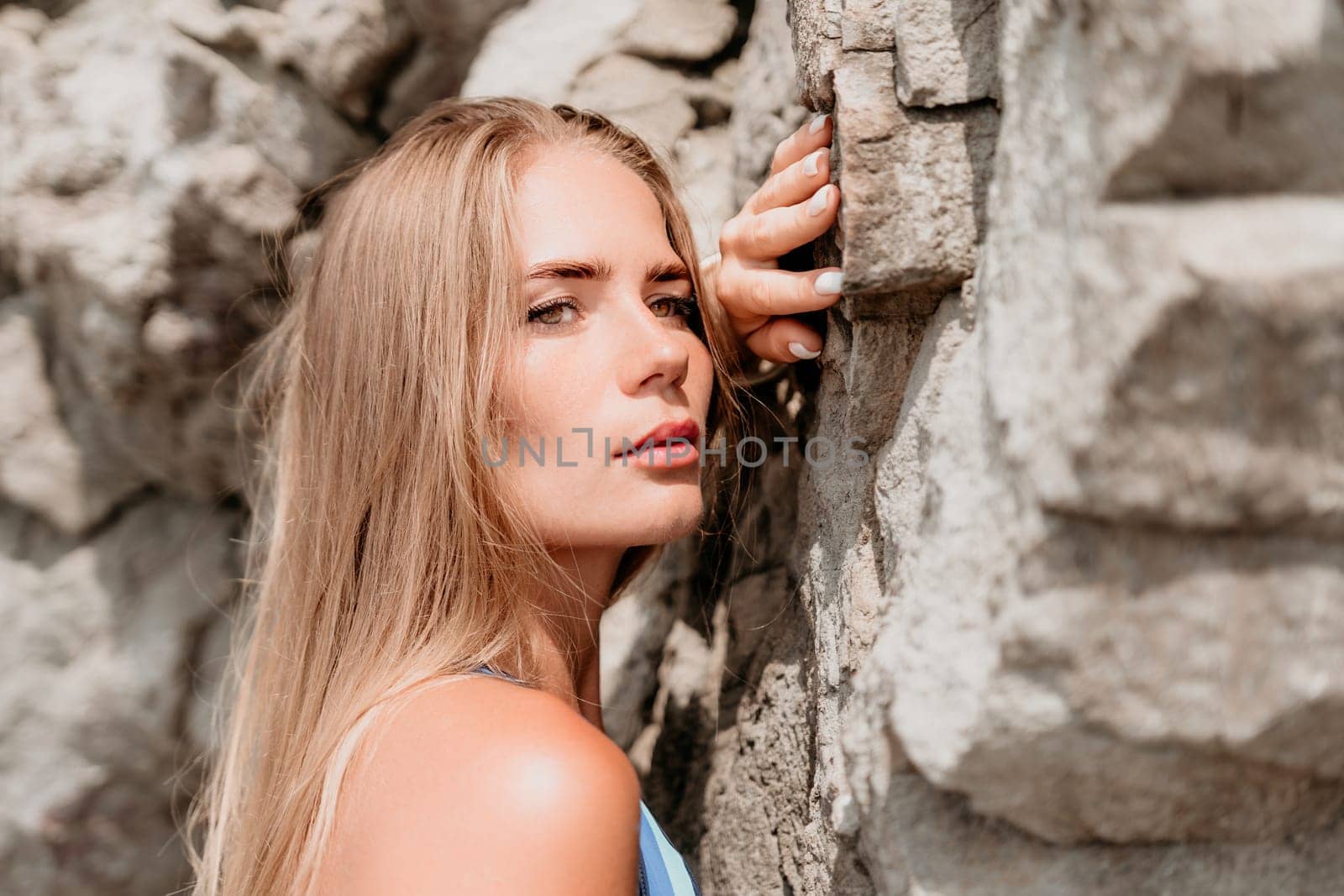 Woman travel sea. Young Happy woman in a long red dress posing on a beach near the sea on background of volcanic rocks, like in Iceland, sharing travel adventure journey