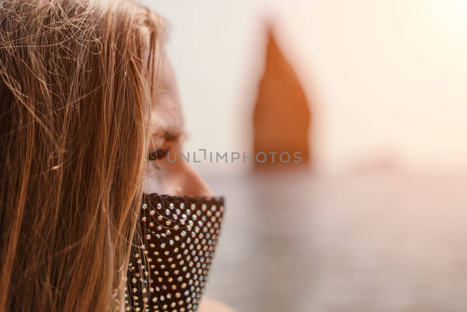 Woman summer travel sea. Happy tourist in black mask enjoy taking picture outdoors for memories. Woman traveler posing on the beach at sea surrounded by volcanic mountains, sharing travel adventure by panophotograph