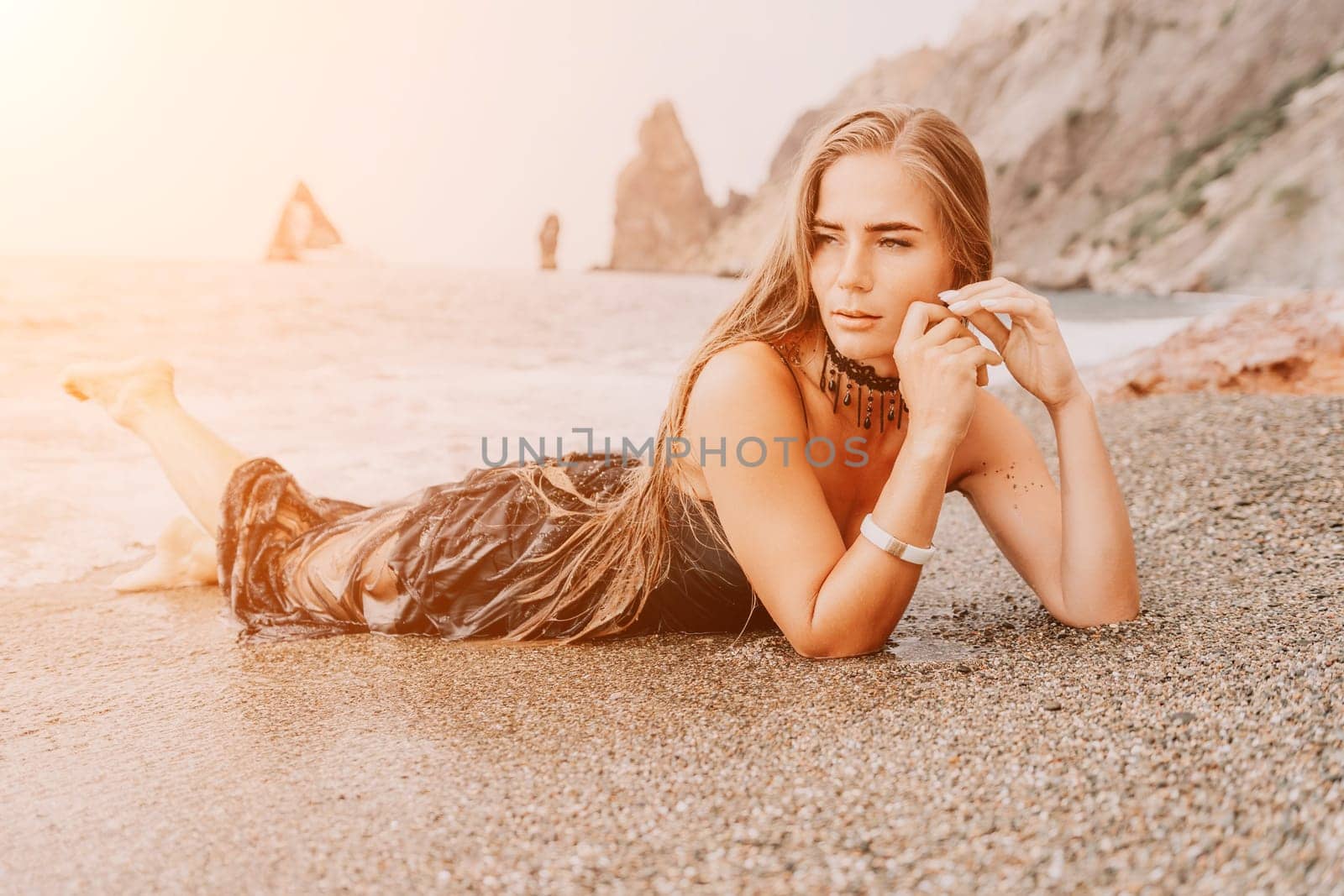 Woman summer travel sea. Happy tourist in black dress enjoy taking picture outdoors for memories. Woman traveler posing on sea beach surrounded by volcanic mountains, sharing travel adventure journey by panophotograph