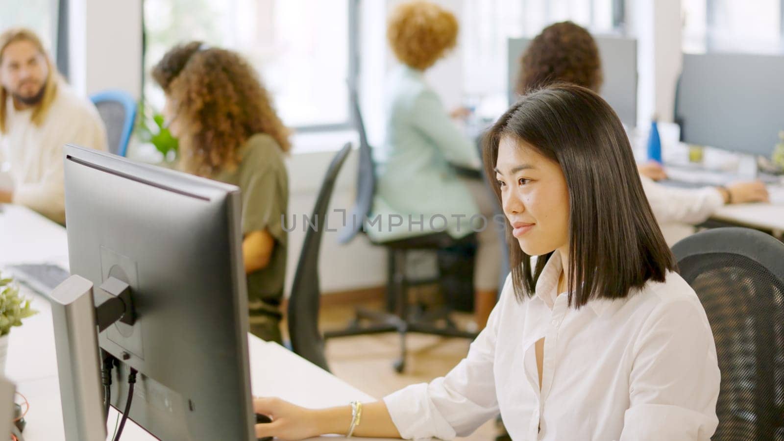Asian woman working happily in a coworking space by ivanmoreno