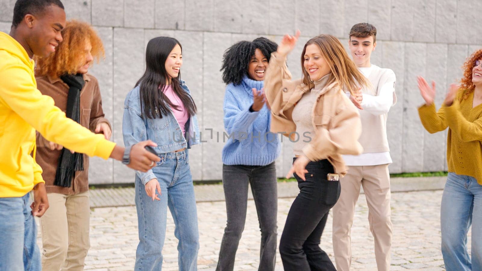 Young group of multi-ethnic happy friends dancing excited in the city