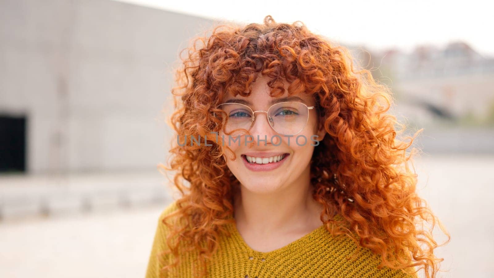 Redhead woman with curly long hair smiling at camera by ivanmoreno