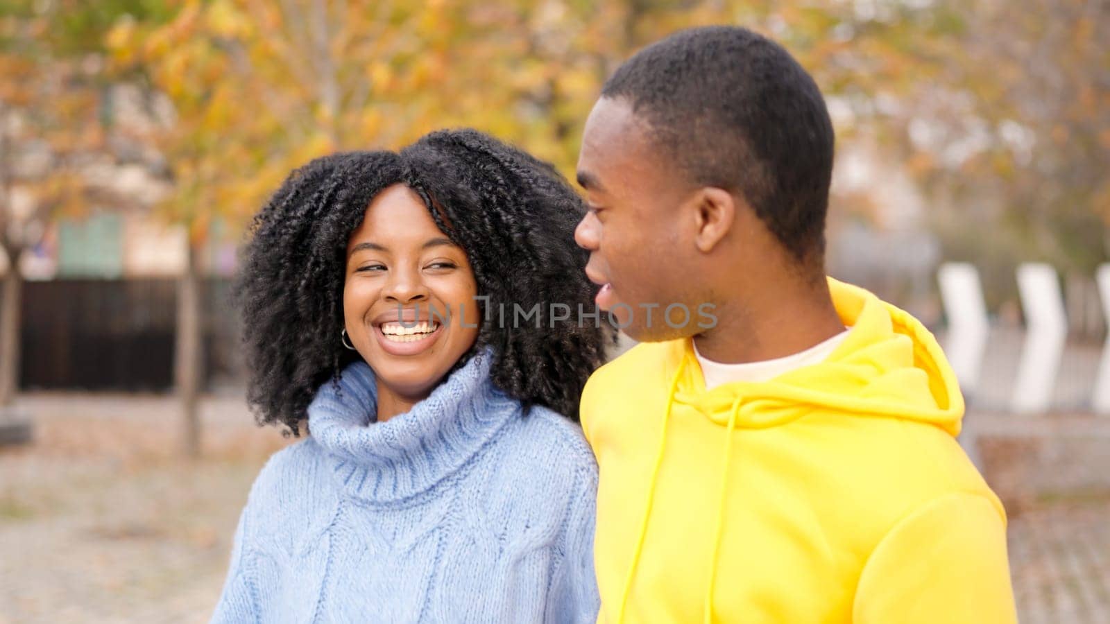 Young african couple flirting while walking together along a street