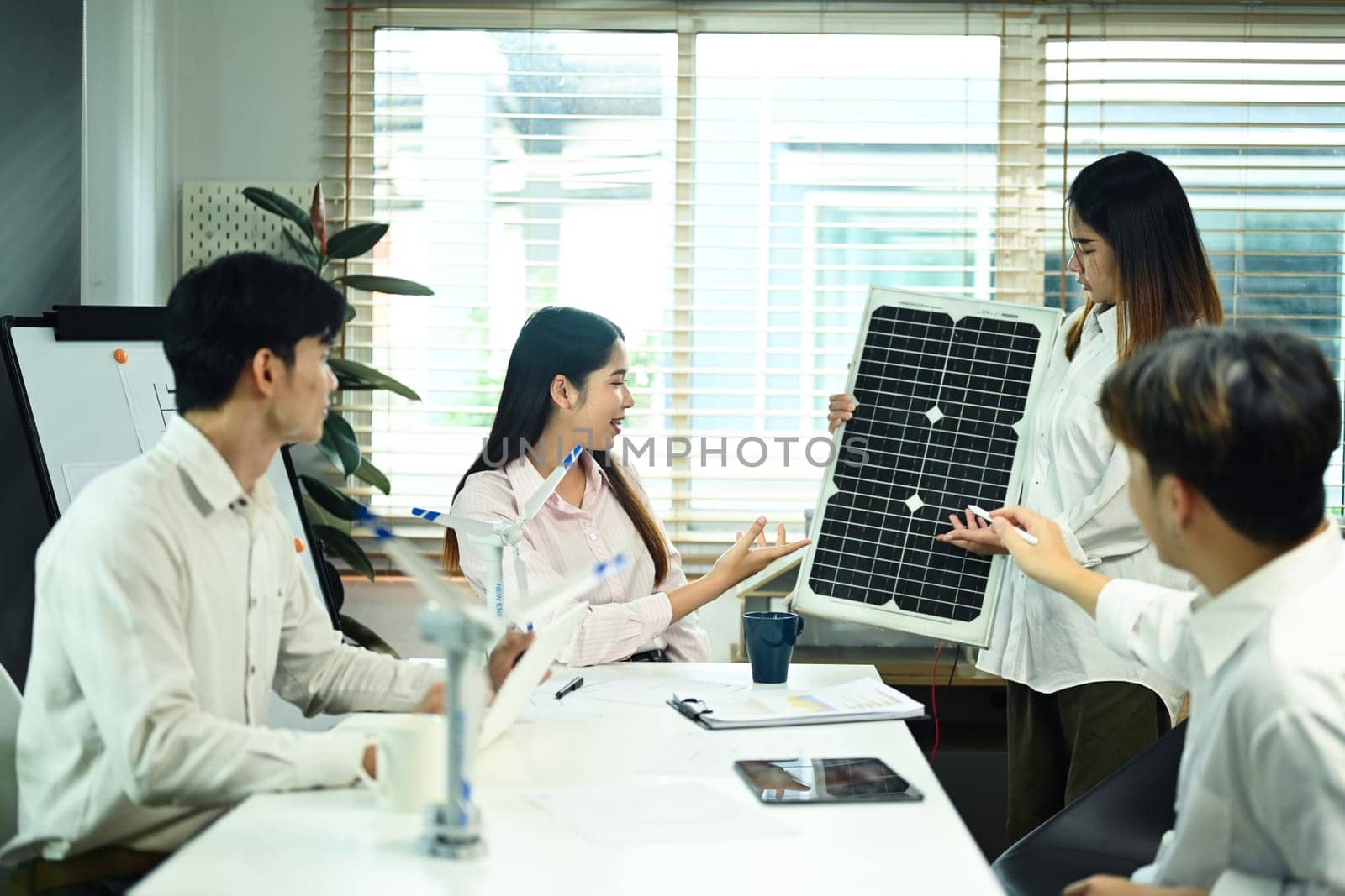 Group of engineers developing solar panel for alternative energy at meeting. Green alternative energy concept.