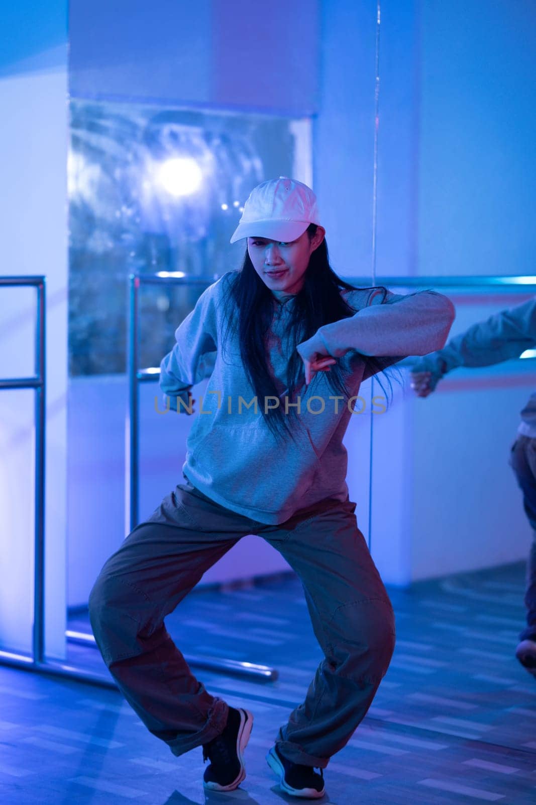 Young Asian woman practicing modern dance styles in a studio with neon light.