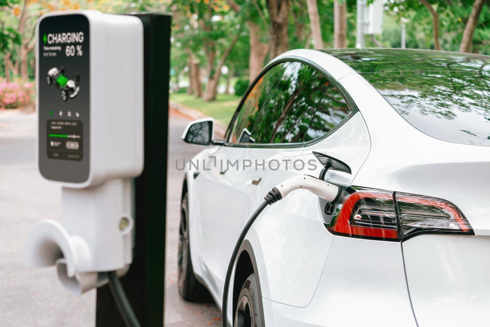 EV electric vehicle recharging battery from EV charging station in national park or outdoor forest scenic. Natural protection with eco friendly EV car travel in the summer woods. Exalt