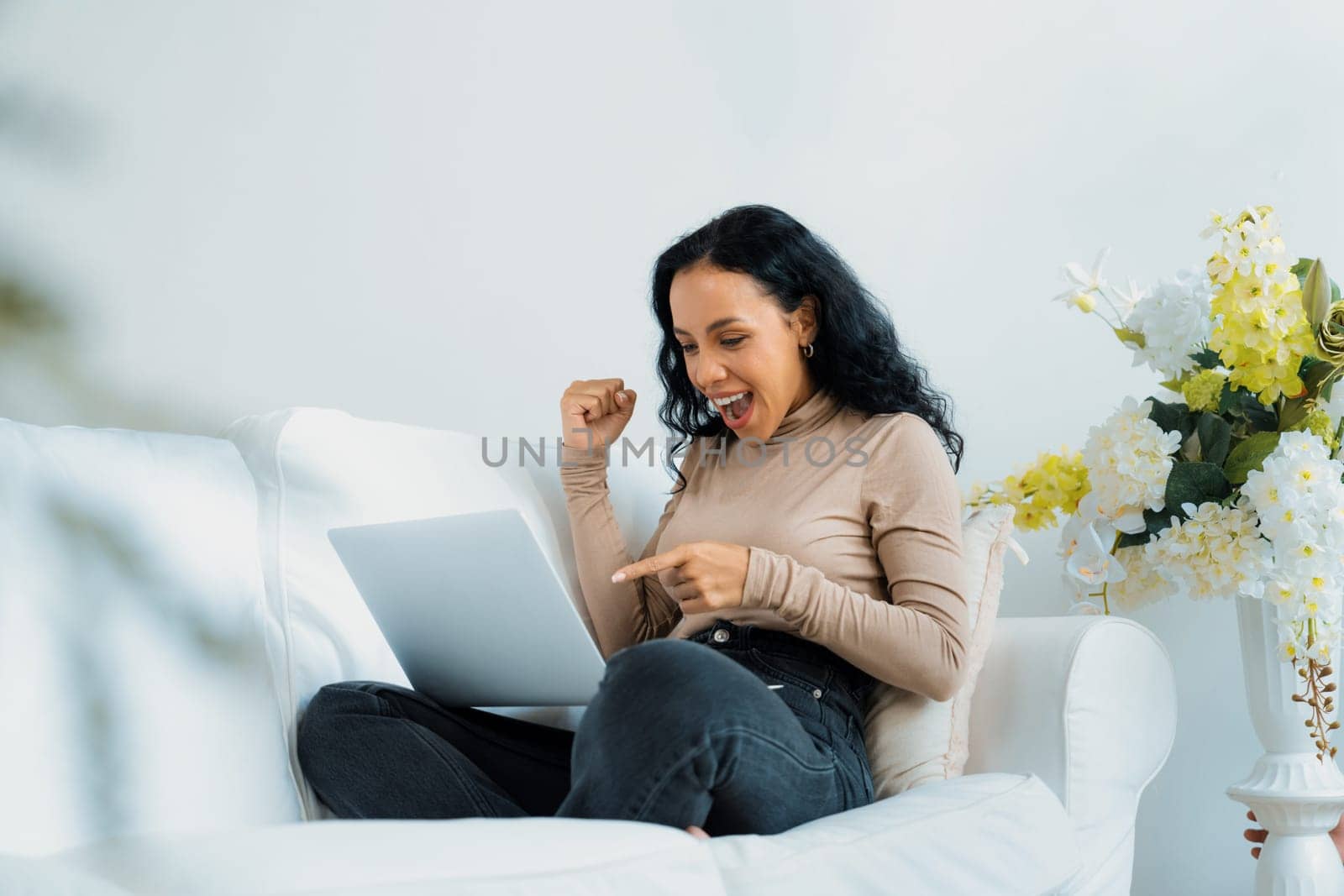 Successful African-American businesswoman feel happy at crucial work on laptop computer while sitting on sofa couch at home