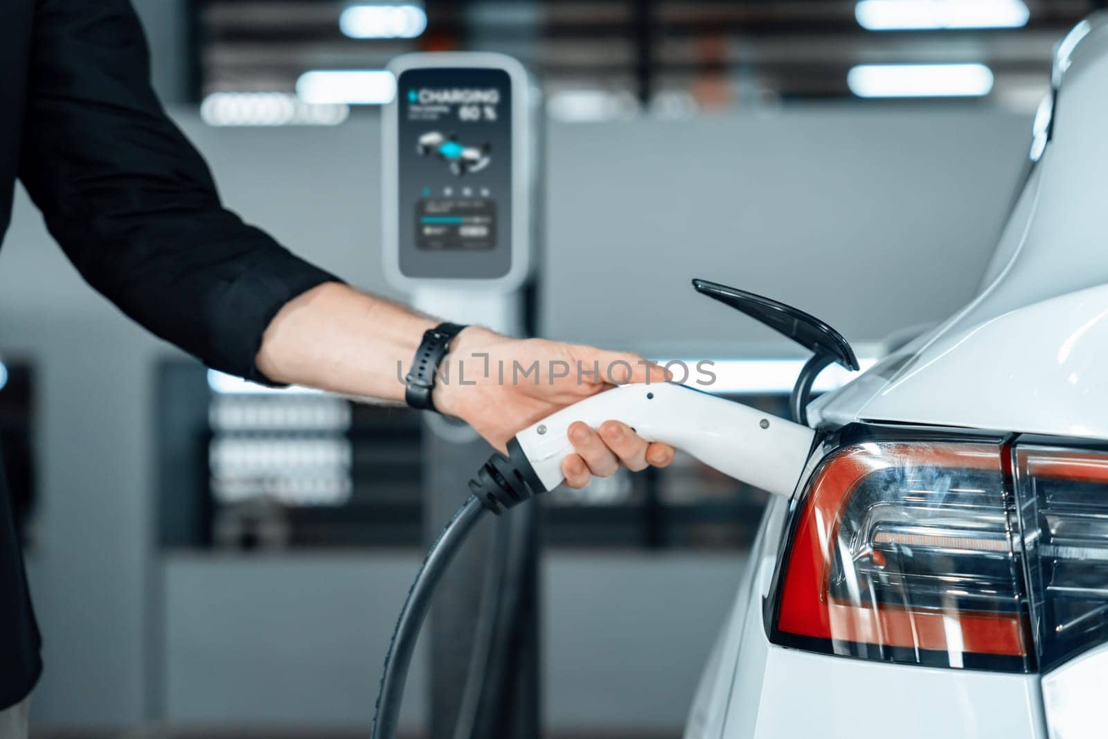 Young man travel with EV electric car to shopping center parking lot charging in downtown city showing urban sustainability lifestyle by green clean rechargeable energy of electric vehicle innards