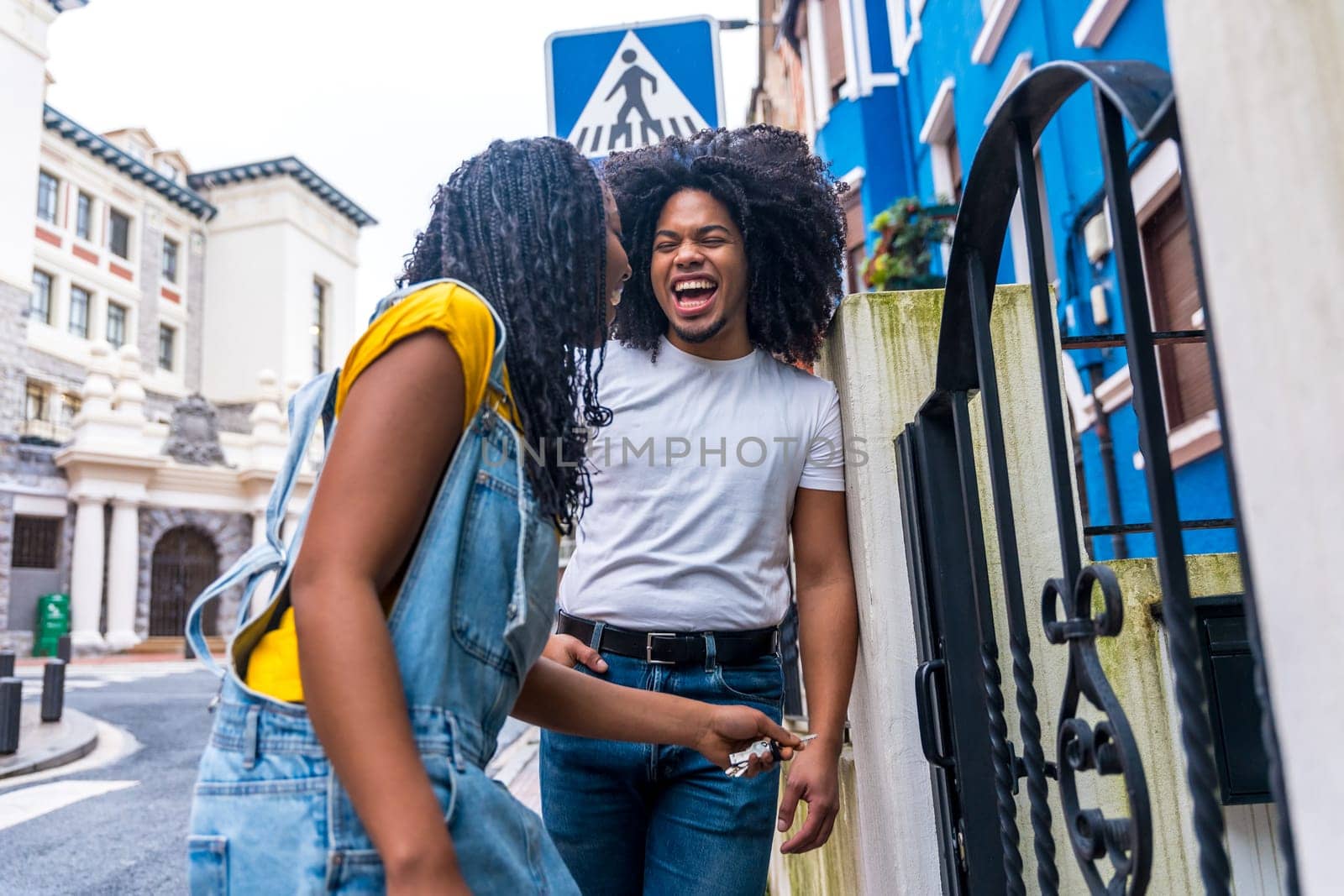 Low angle view portrait of a happy african friends laughing in the entrance of a house