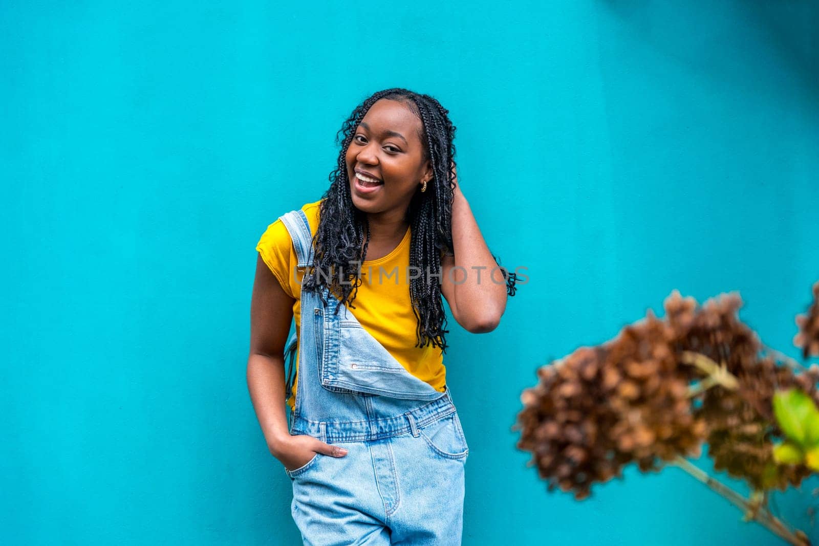 Horizontal portrait with copy space and focus on a casual african woman posing shy leaning on a blue urban wall