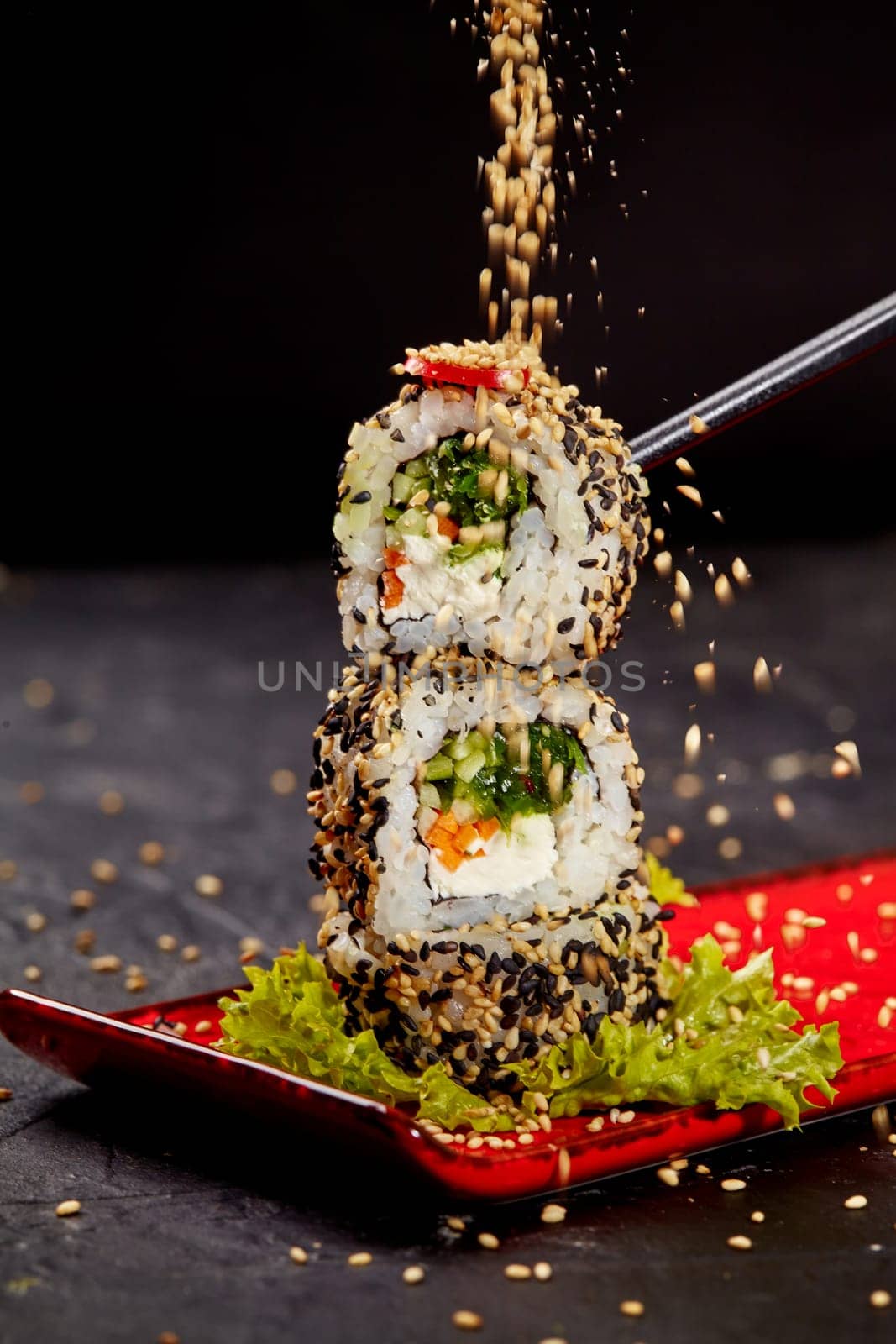 Sesame seeds sprinkling on vegetarian sushi roll tower by nazarovsergey