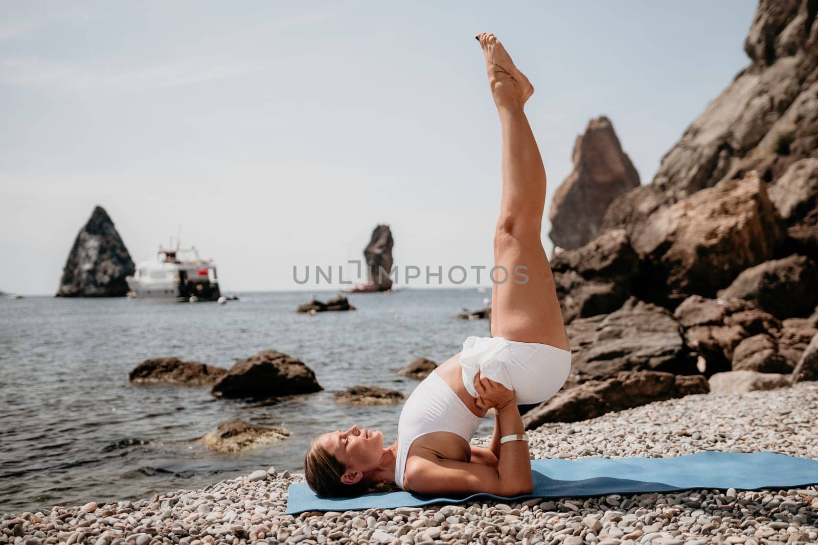 Woman sea yoga. Two Happy women meditating in yoga pose on the beach, ocean and rock mountains. Motivation and inspirational fit and exercising. Healthy lifestyle outdoors in nature, fitness concept. by panophotograph