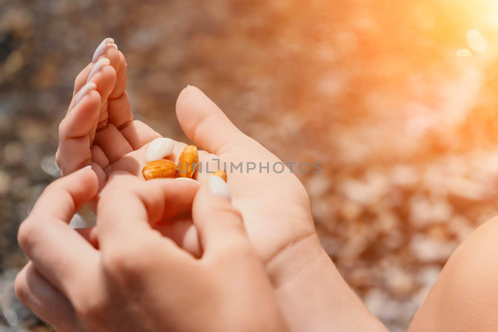 Woman eating milky almond nuts. A young caucasian woman choping fresh green almond after morning fitness yoga near sea. Only hands are visibly. Healthy vegan food. Slow motion. Close up