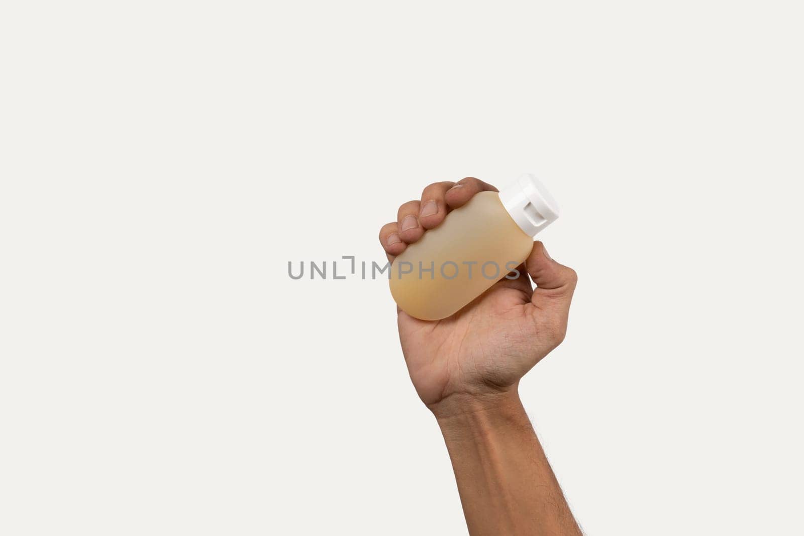 Black male hand holding shaampoo or gel container mockup on grey background. by TropicalNinjaStudio