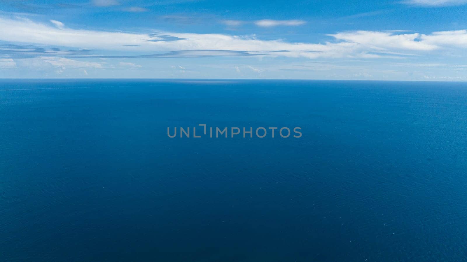 Blue sea water with waves against sky and clouds. Seascape in the tropics. Borneo, Malaysia.