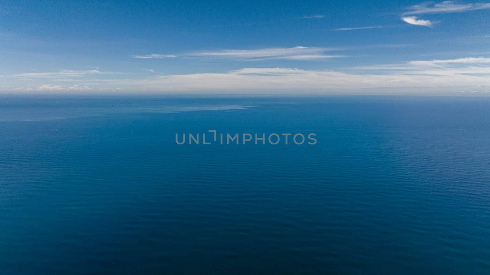 Aerial drone of open blue sea with waves against the sky and clouds. Seascape in the tropics. Borneo, Malaysia.