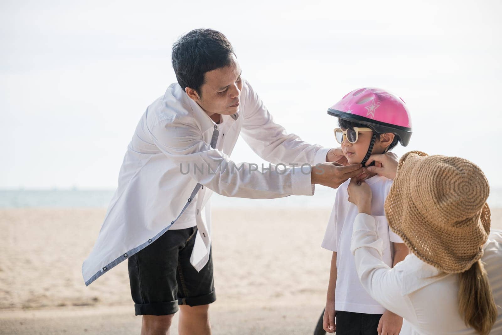 A beach travel concept unfolds, Father with a safety helmet teaches his cheerful son the balance and freedom of bicycle riding a heartwarming tourism day filled with family joy.