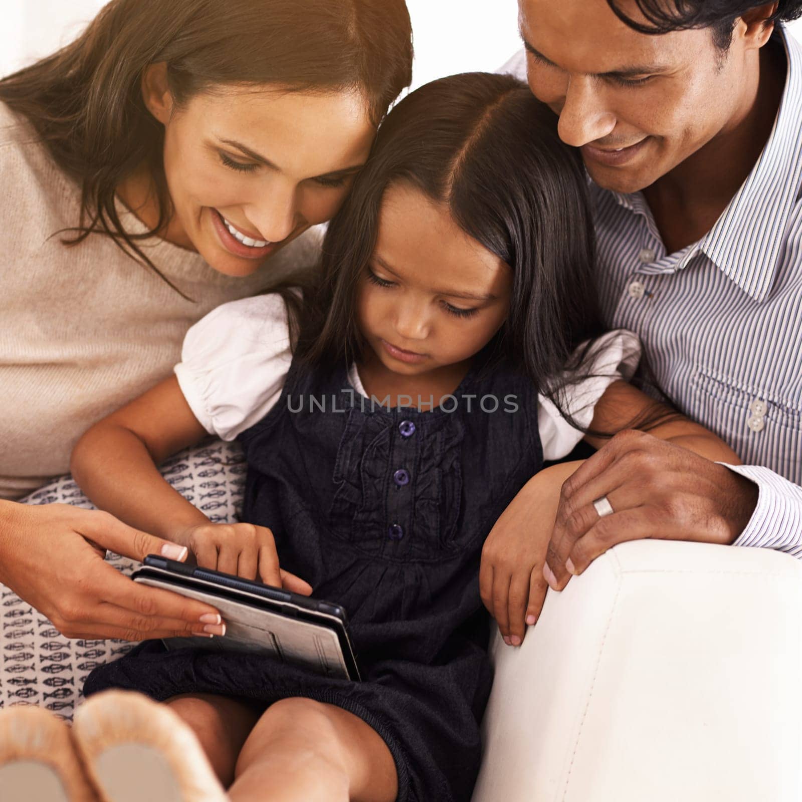 Happy parents, child and tablet for entertainment, social media or games on sofa at home. Mother, father and daughter on technology for online streaming, movie or reading ebook in elearning at house by YuriArcurs