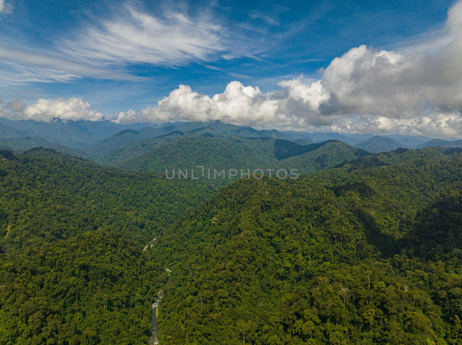 Aerial view of mountains covered rainforest, trees and blue sky with clouds. Sumatra, Indonesia.