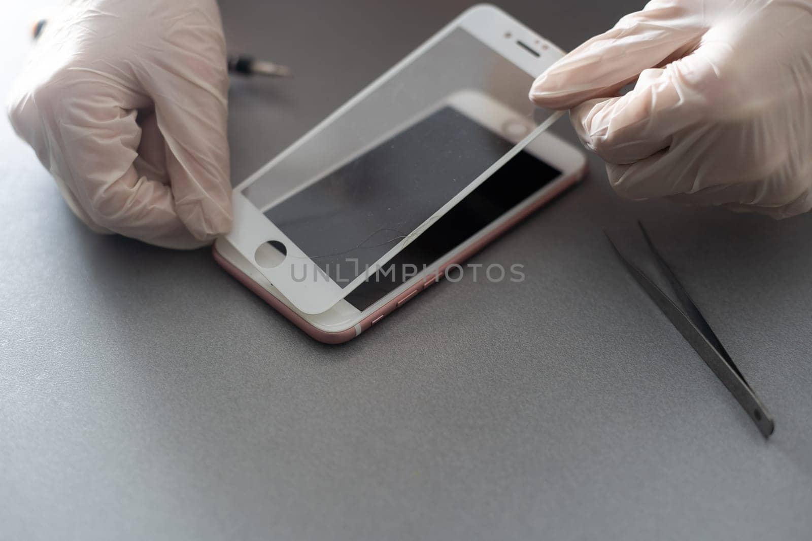 a person places a protective glass or film on a smartphone. copy space. by Andelov13