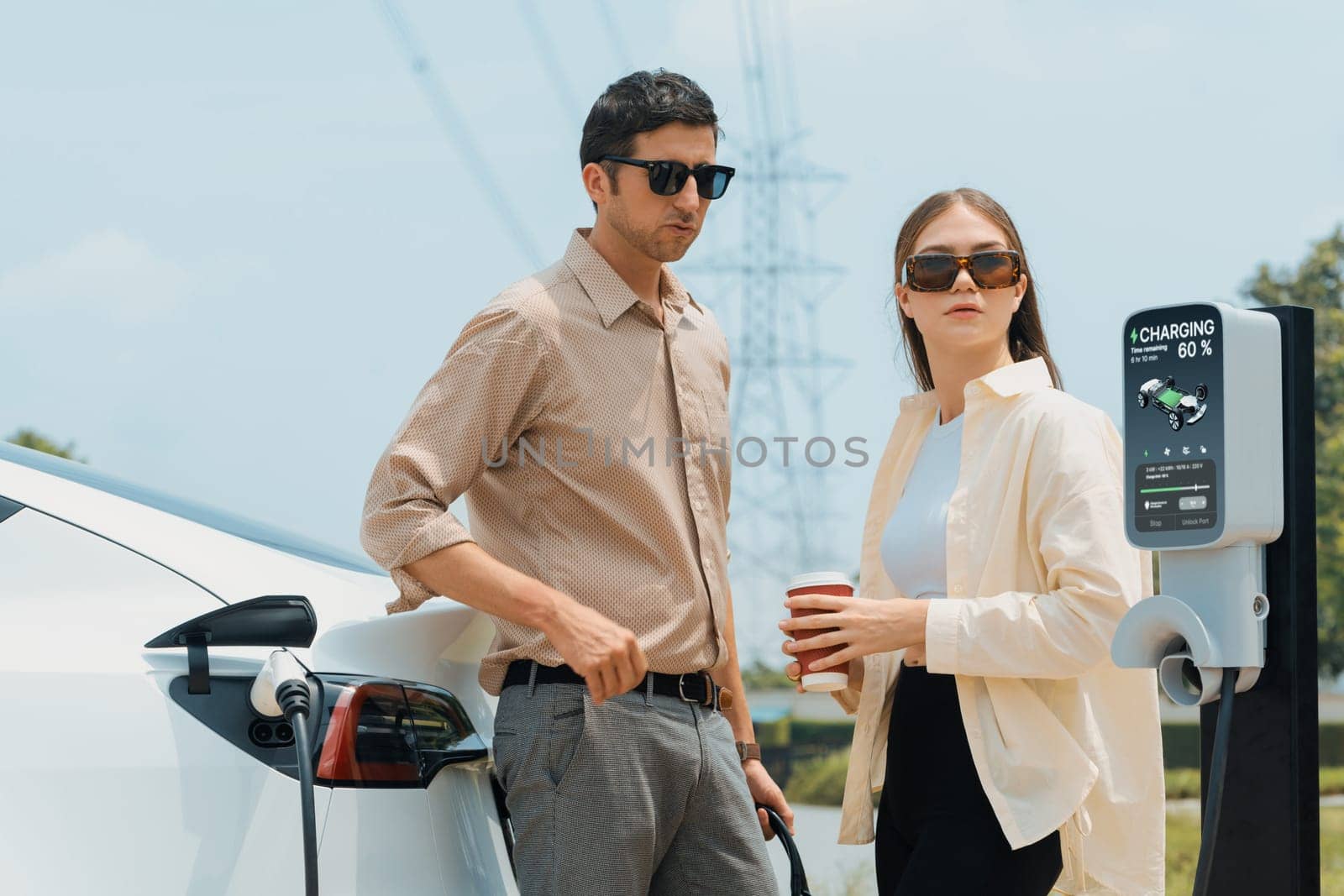 Young couple recharge EV car battery at charging station. Expedient by biancoblue