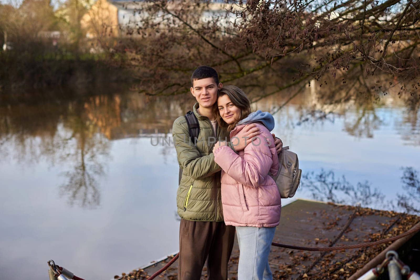 Embracing Moments: Beautiful 35-Year-Old Mother and 17-Year-Old Son in Winter or Autumn Park by Neckar River, Bietigheim-Bissingen, Germany by Andrii_Ko