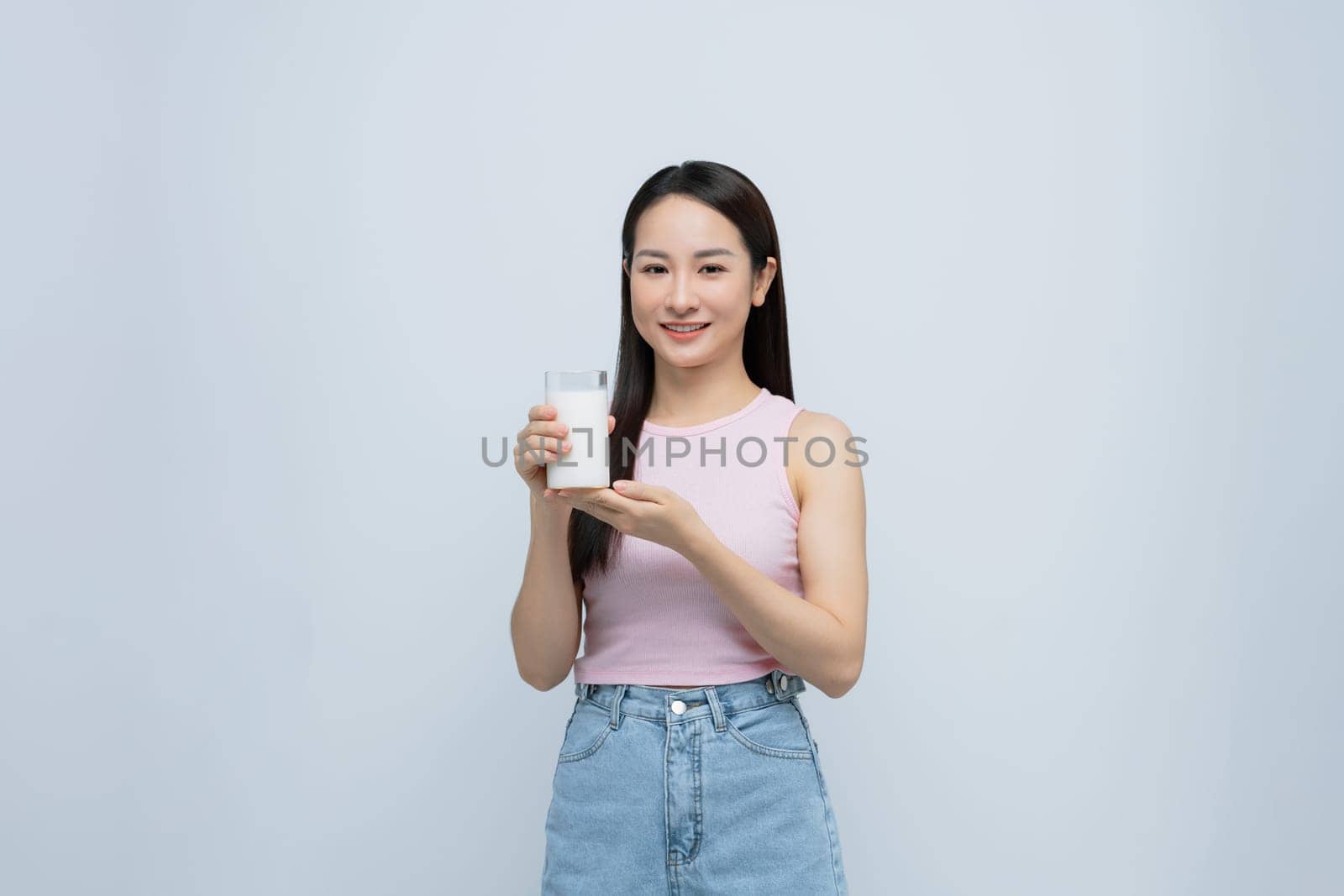 Healthy Asian woman drinking a glass of milk isolated on white background. by makidotvn