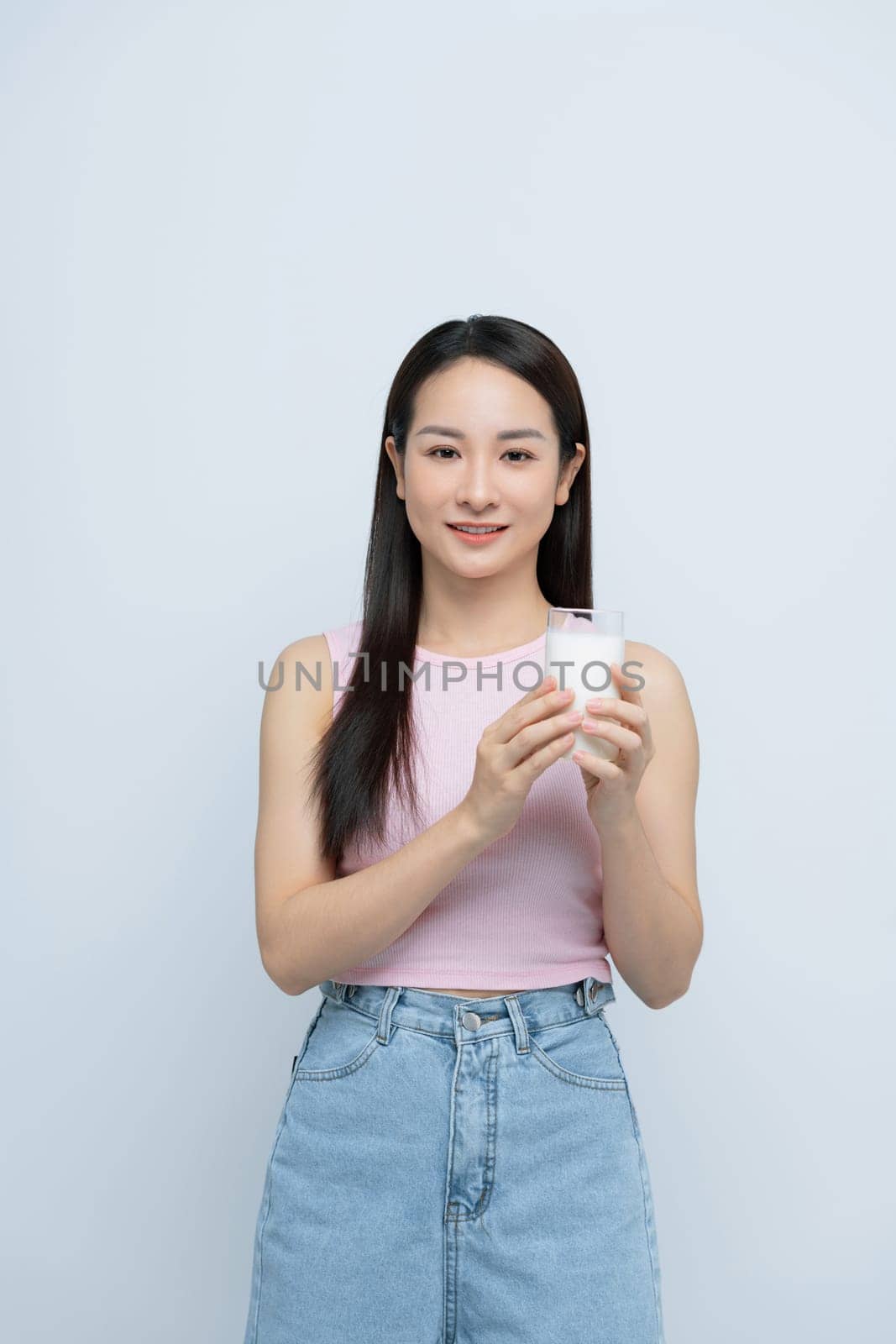 Young woman enjoying a glass of milk isolated over white background