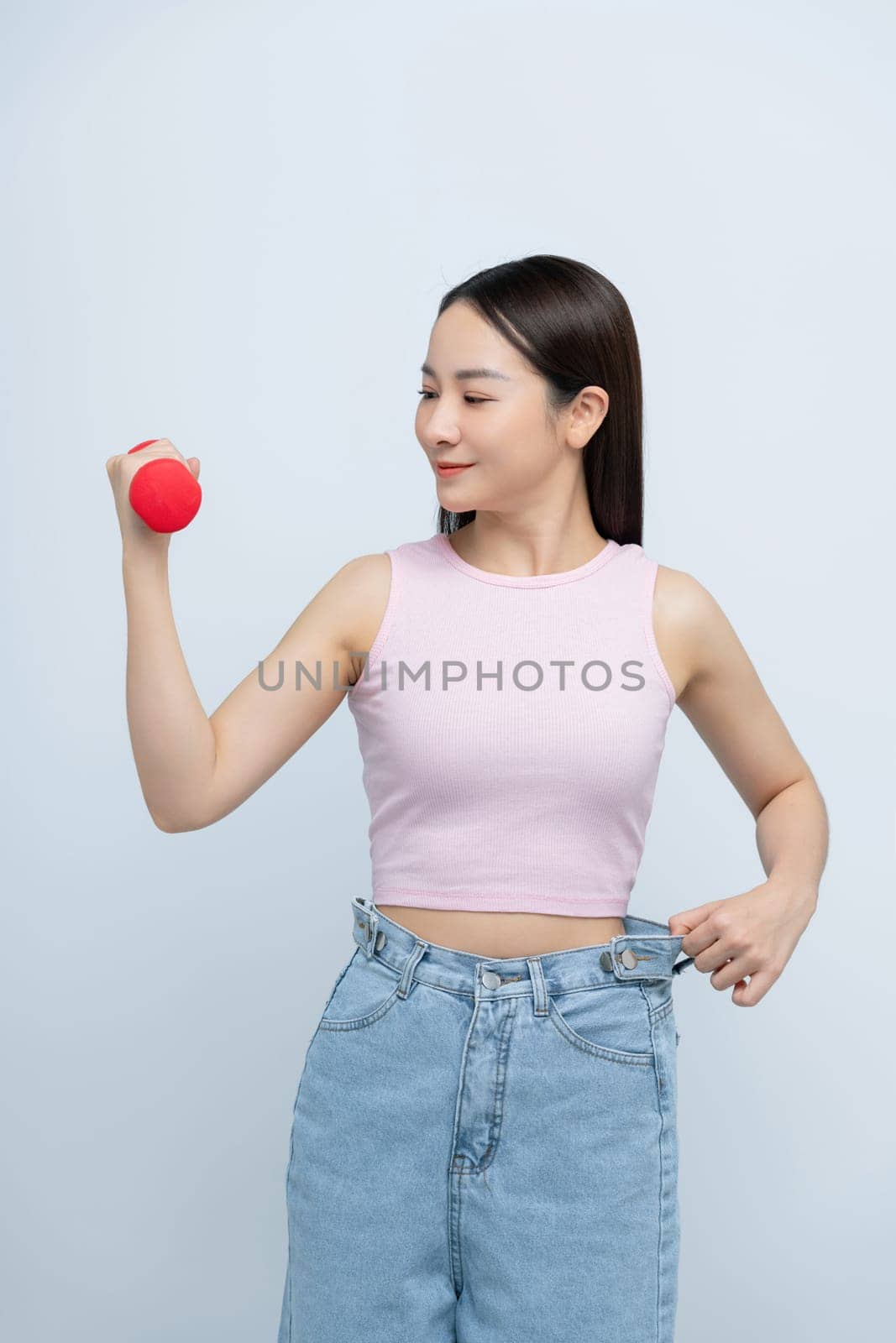 Woman lifting dumbbell in oversized jeans unwearable