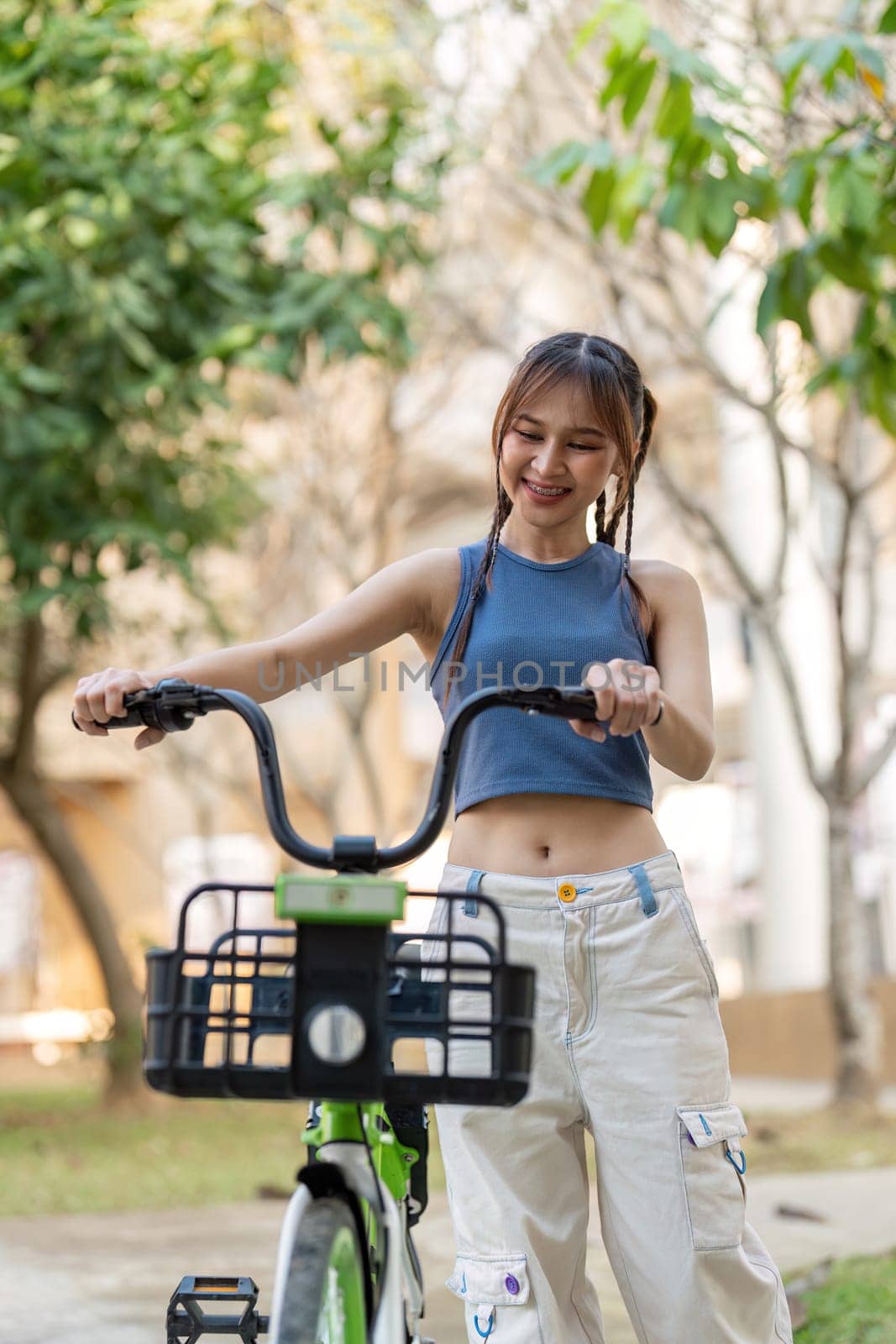 Happy young asian woman in casual clothes enjoy riding bicycle at the park for recreation by nateemee