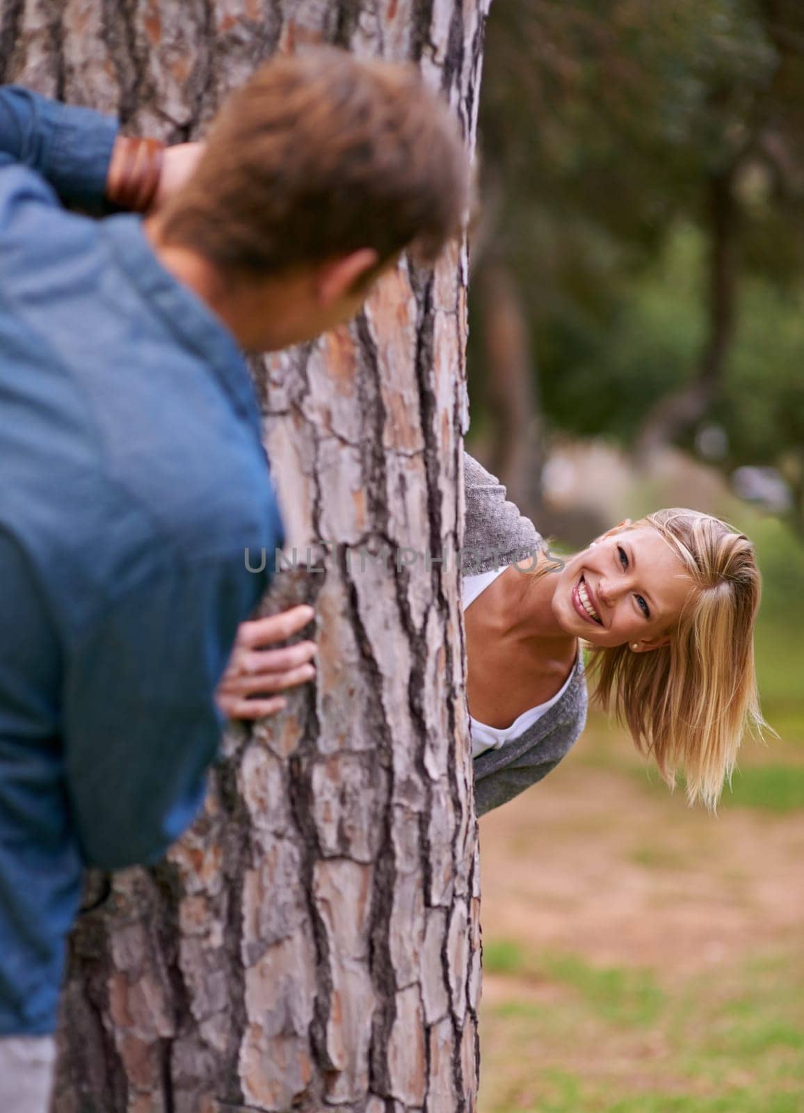 Couple, park and smile with playing for hide and seek, love and happiness in outdoor setting in Los Angeles. Relationship, romance and fun day in forest for lifestyle, wellness and relax for bonding.