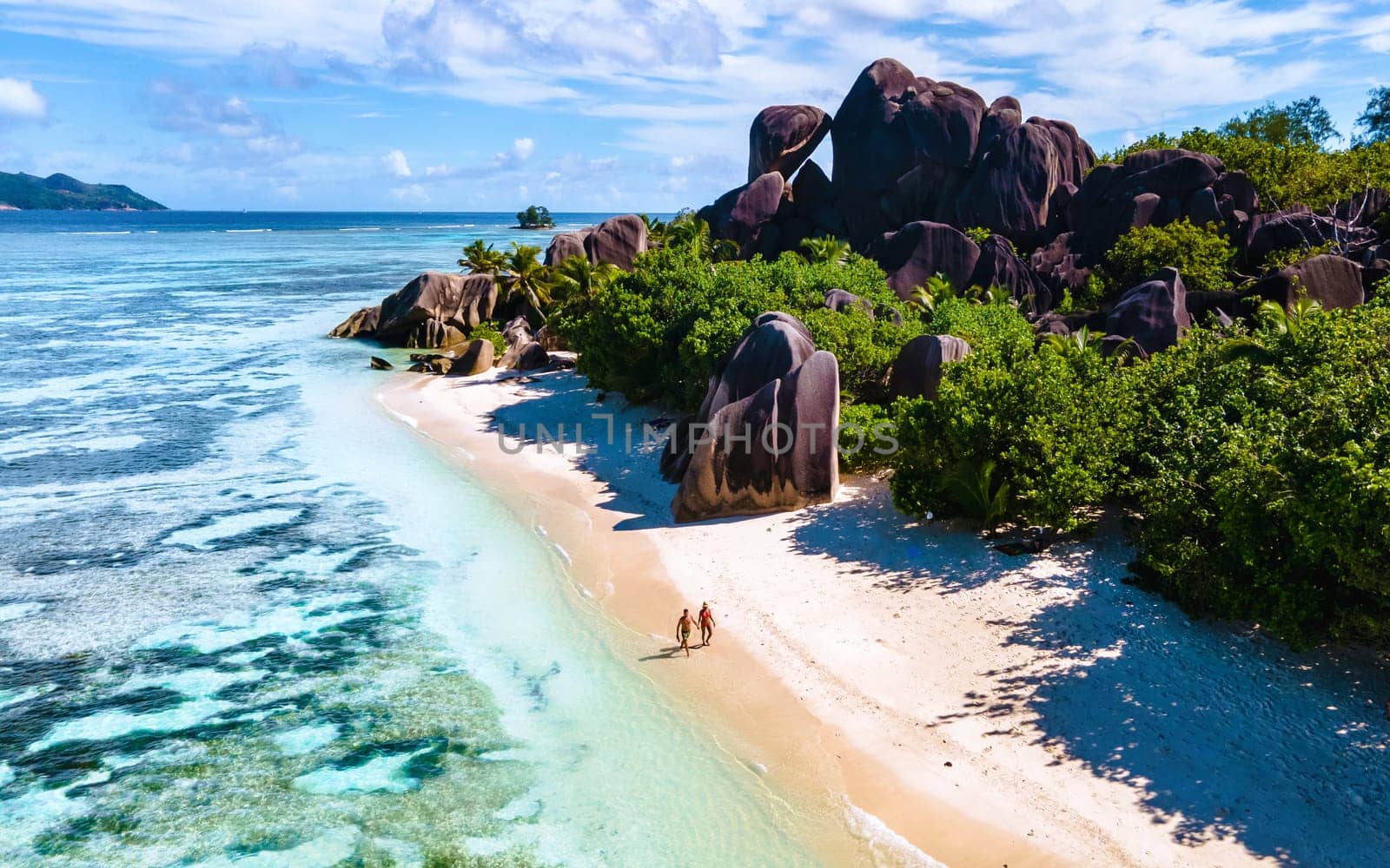 Anse Source d'Argent beach, La Digue Island, Seyshelles, Drone aerial view of La Digue Seychelles bird eye view, couple men and woman walking at the beach during sunset at a luxury vacation by fokkebok