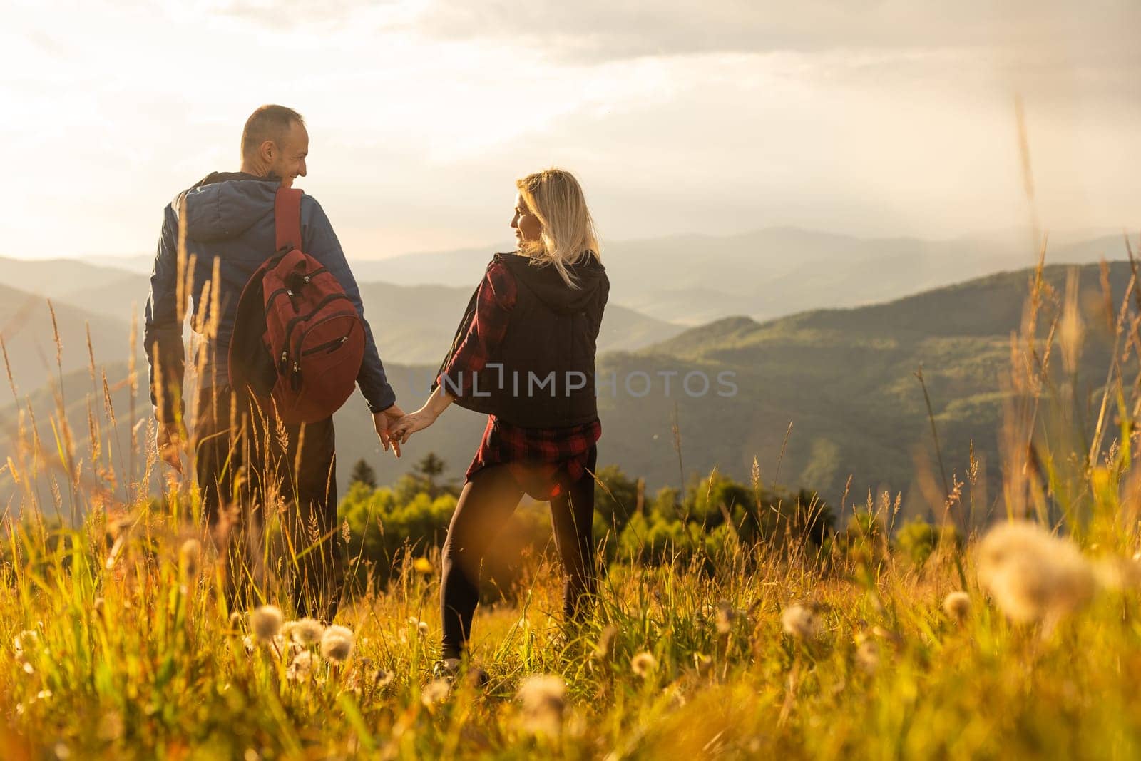 travel to mountains, tourists hikers with backpacks at sunset enjoying panoramic view by Andelov13