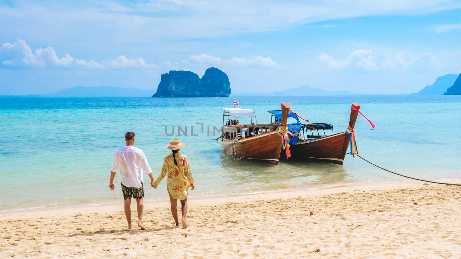 a couple of men and woman walking on the beach with longtail boats Koh Ngai island Thailand by fokkebok