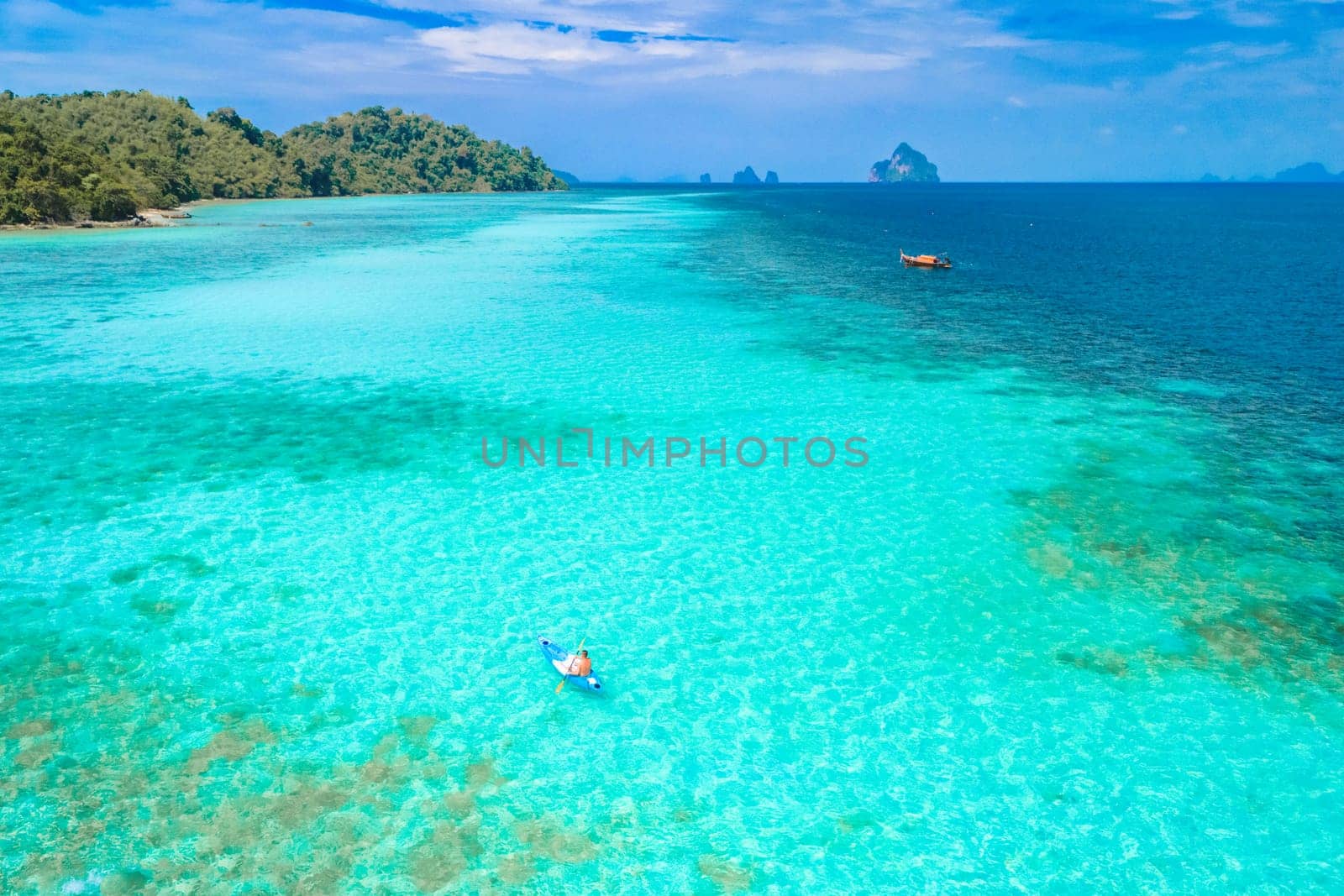 Young man in a kayak at the bleu turqouse colored ocean of Koh Kradan a tropical island with a coral reef in the ocean, Koh Kradan Trang Thailand
