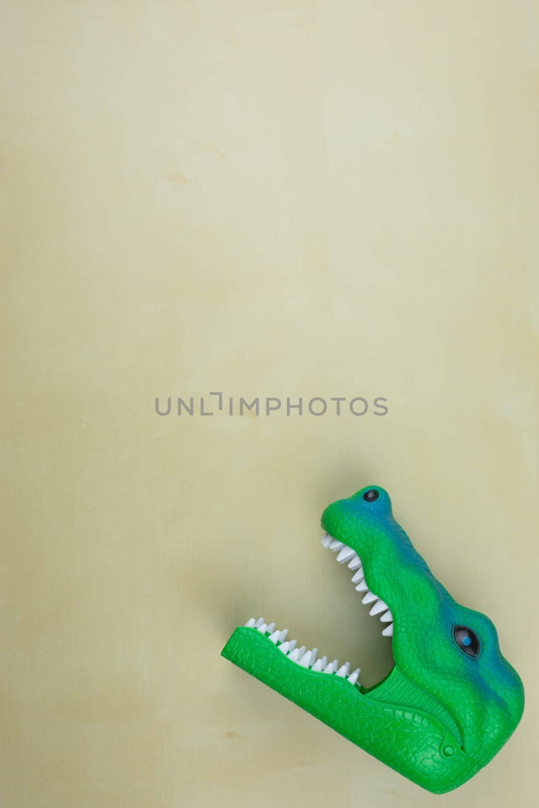 Reptile head toy with open mouth on table with space for text, toy concept