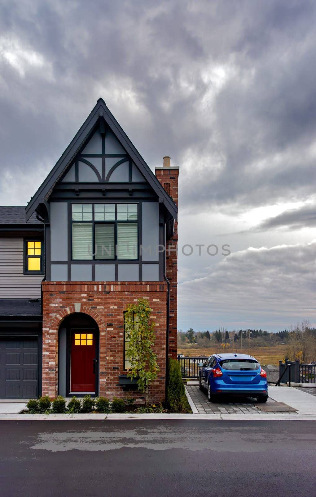 A perfect neighbourhood. Residential townhouse on later evening sky background with blue car parked on side.