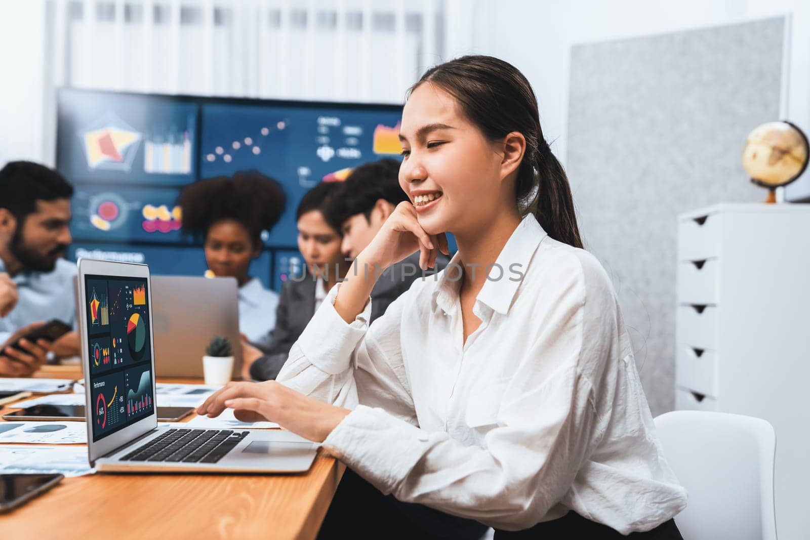 Portrait of happy young asian businesswoman with group of office worker on meeting with screen display business dashboard in background. Confident office lady at team meeting. Concord