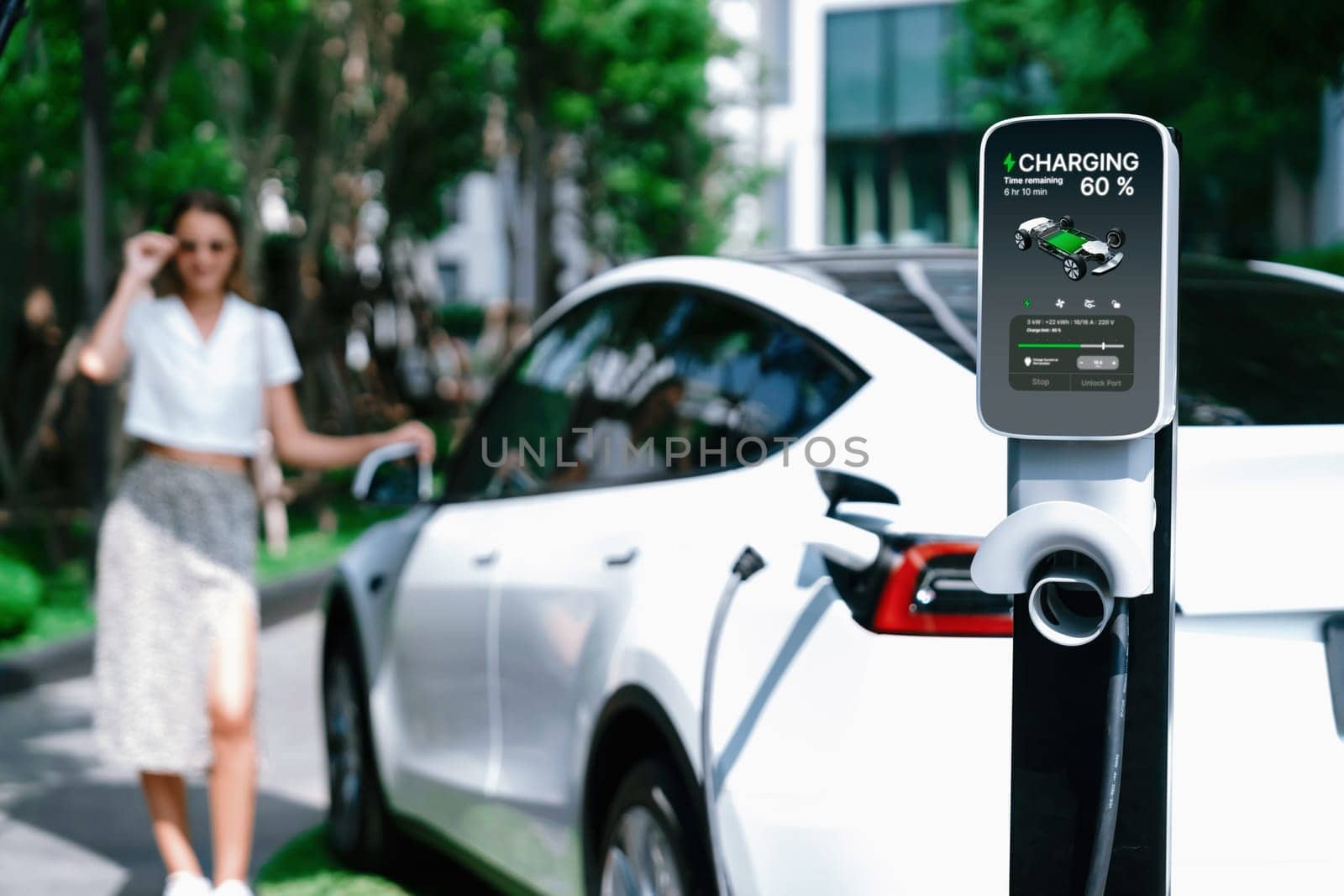 Young woman travel with EV electric car charging in green sustainable city outdoor garden in summer. Urban sustainability lifestyle by green clean rechargeable energy of electric BEV vehicle innards