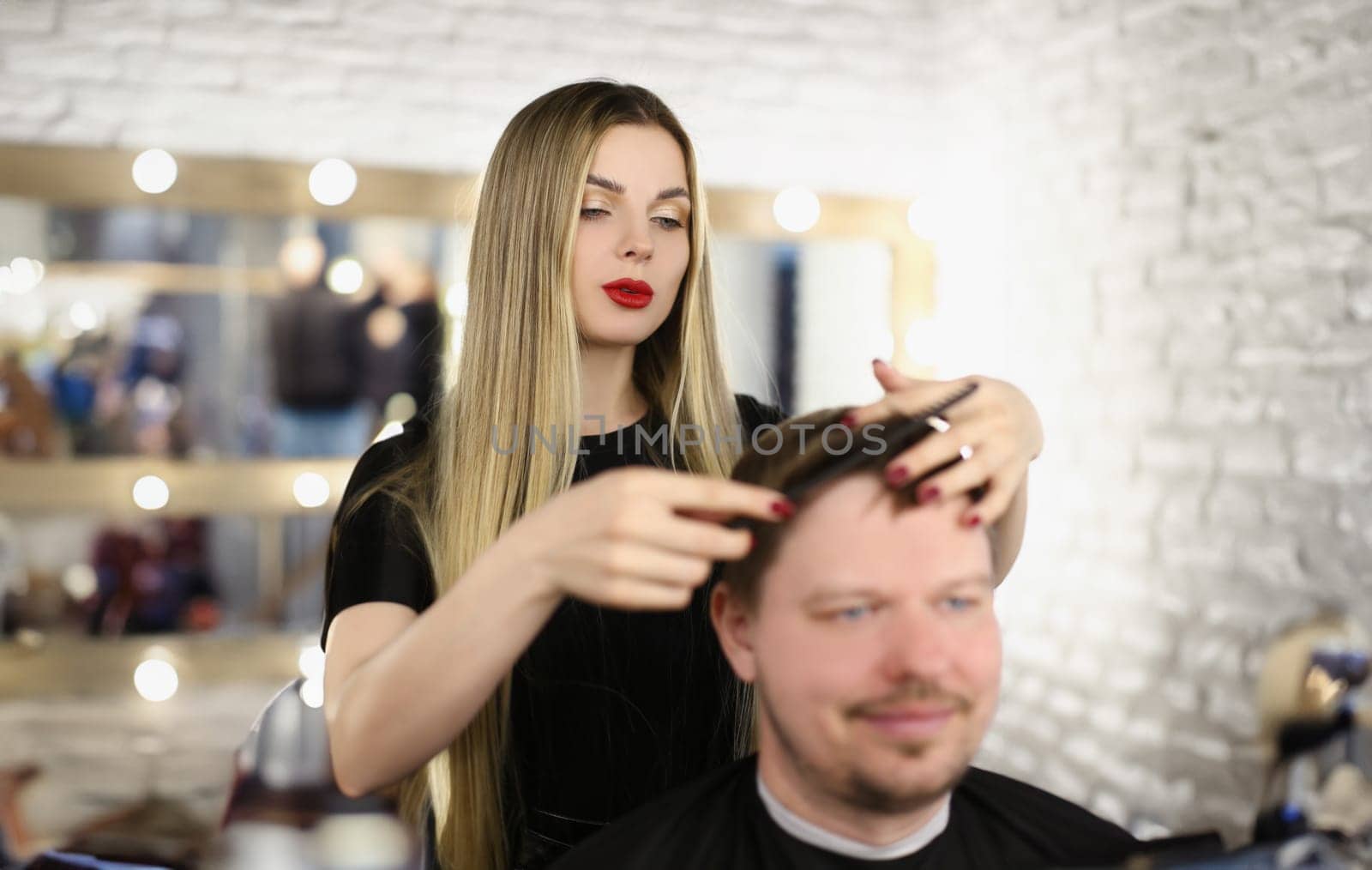 Stylish girl hairdresser combing hair to a man, close-up. Woman master makes a haircut to a guy, fashion