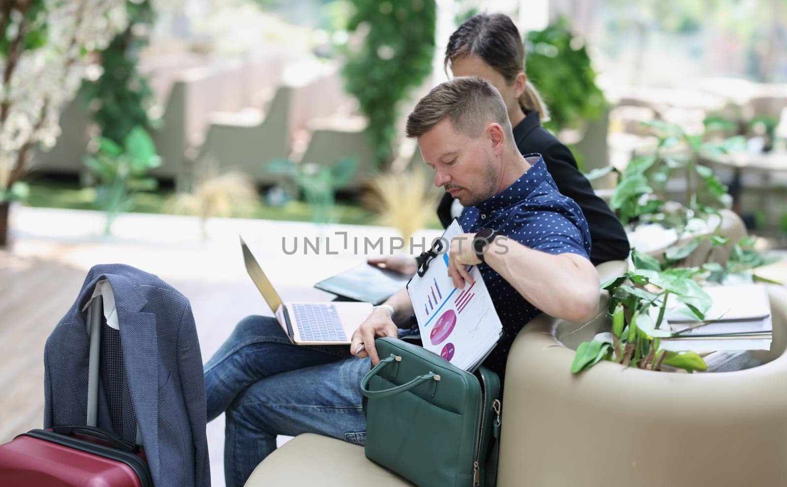 Businessmen with laptops at the airport waiting for boarding, close-up. Flight delay, work remotely, train station