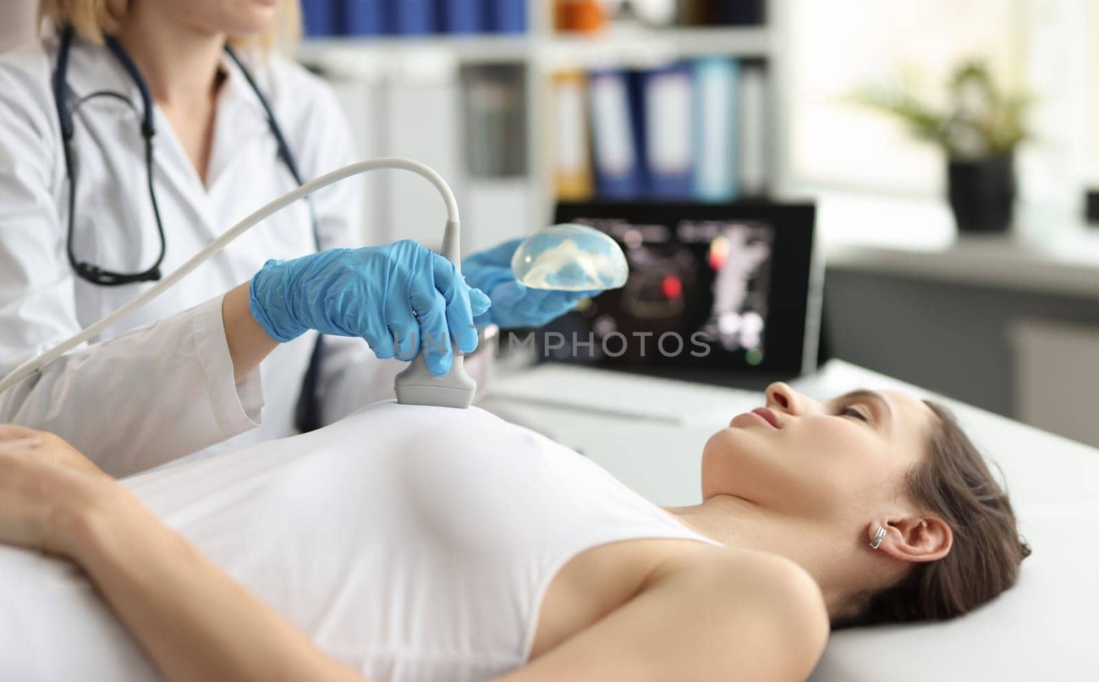 The doctor makes a woman breast ultrasound, close-up. Preparing for mammoplasty, breast cancer treatment