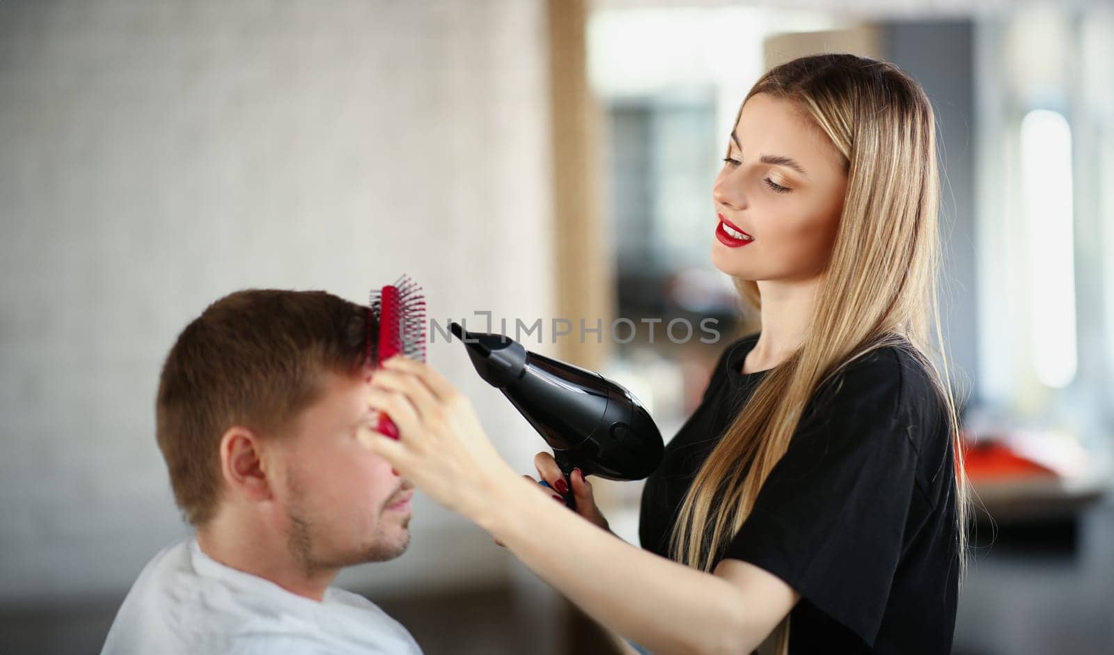 Attractive girl hairdresser doing hair styling to a man by kuprevich