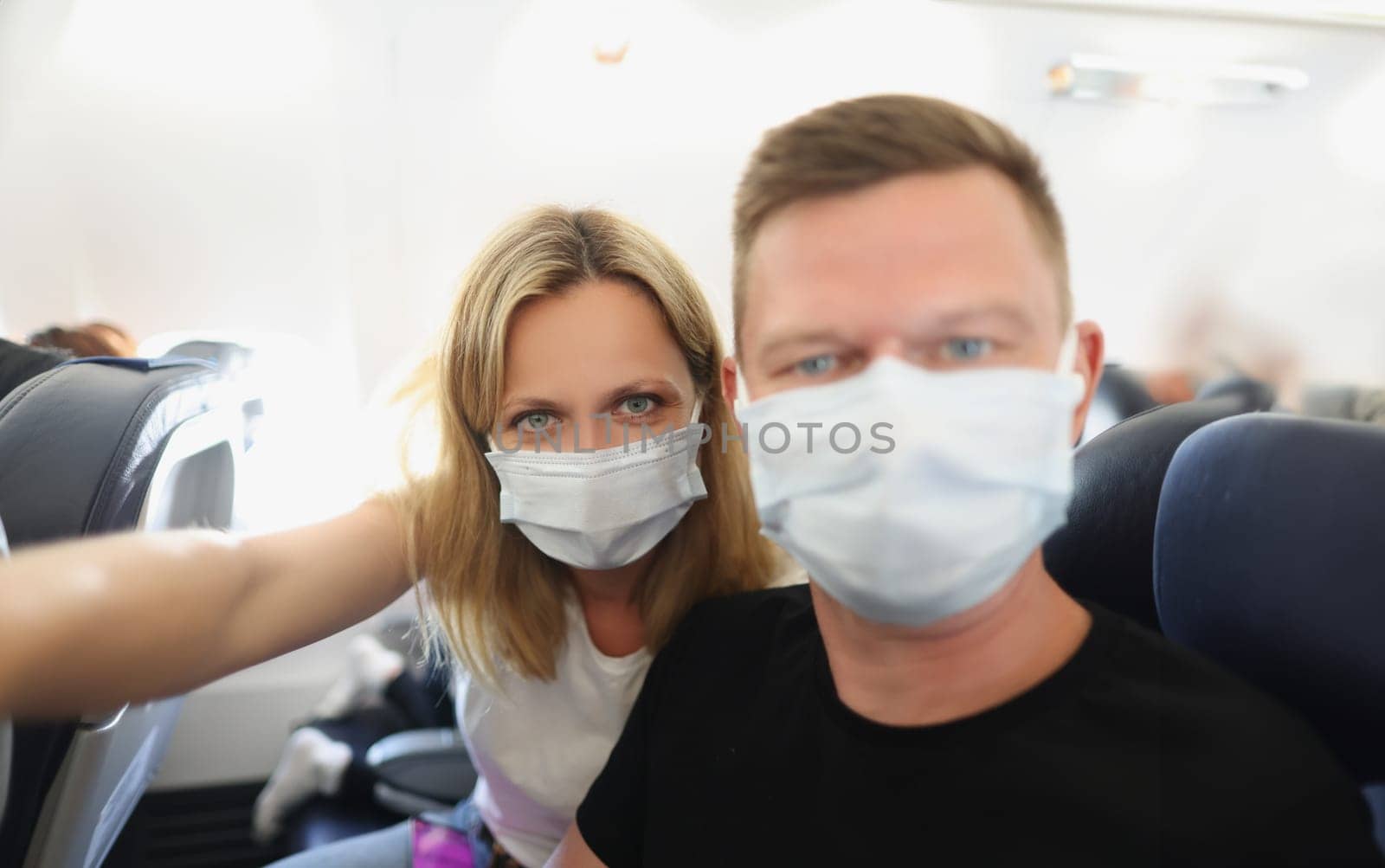 Young family couple in protective masks on the plane by kuprevich