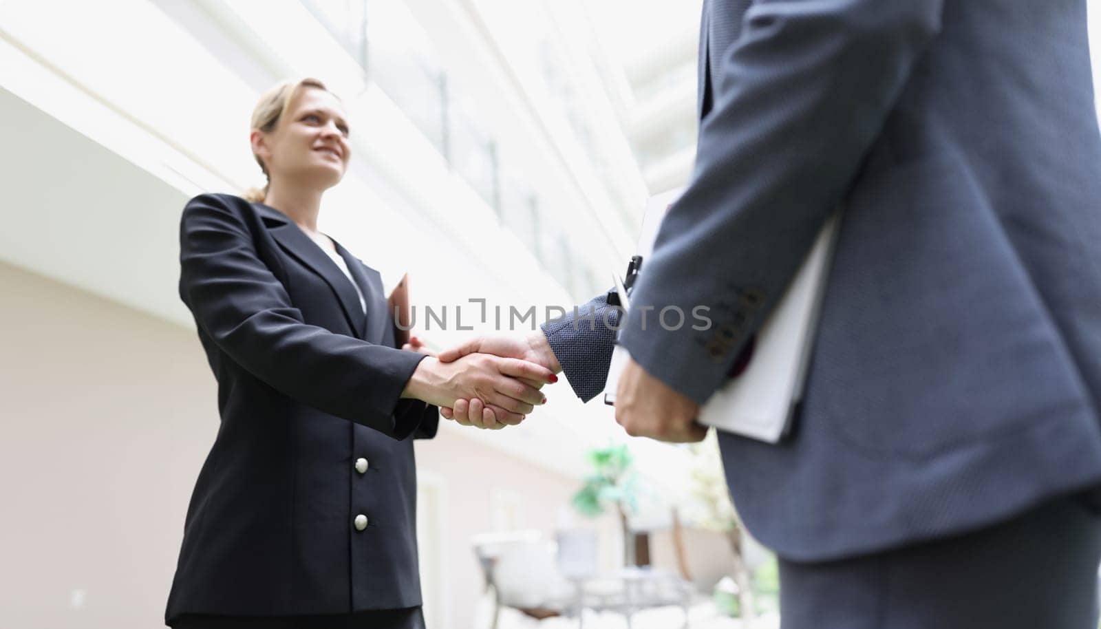 Businessmen in suits shaking hands in the lobby of the building, blurry. Business decisions concept, support gender equality tend