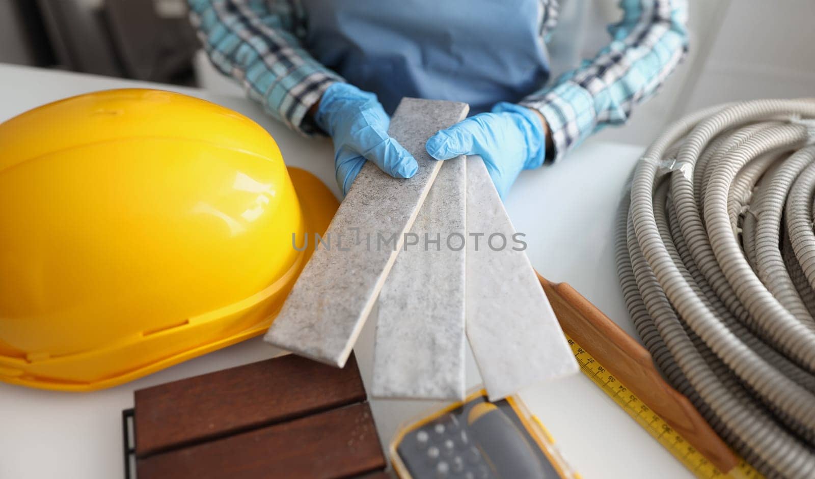 Hands in gloves hold samples of stone tiles, close-up by kuprevich