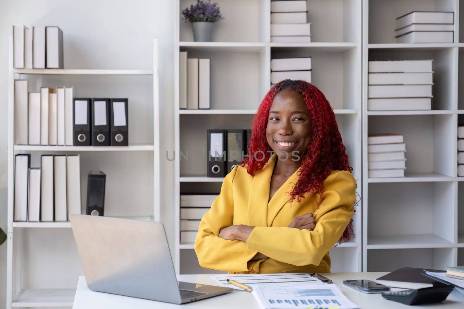 African American businesswoman sitting happy doing accounting and finance work on her desk in the office..