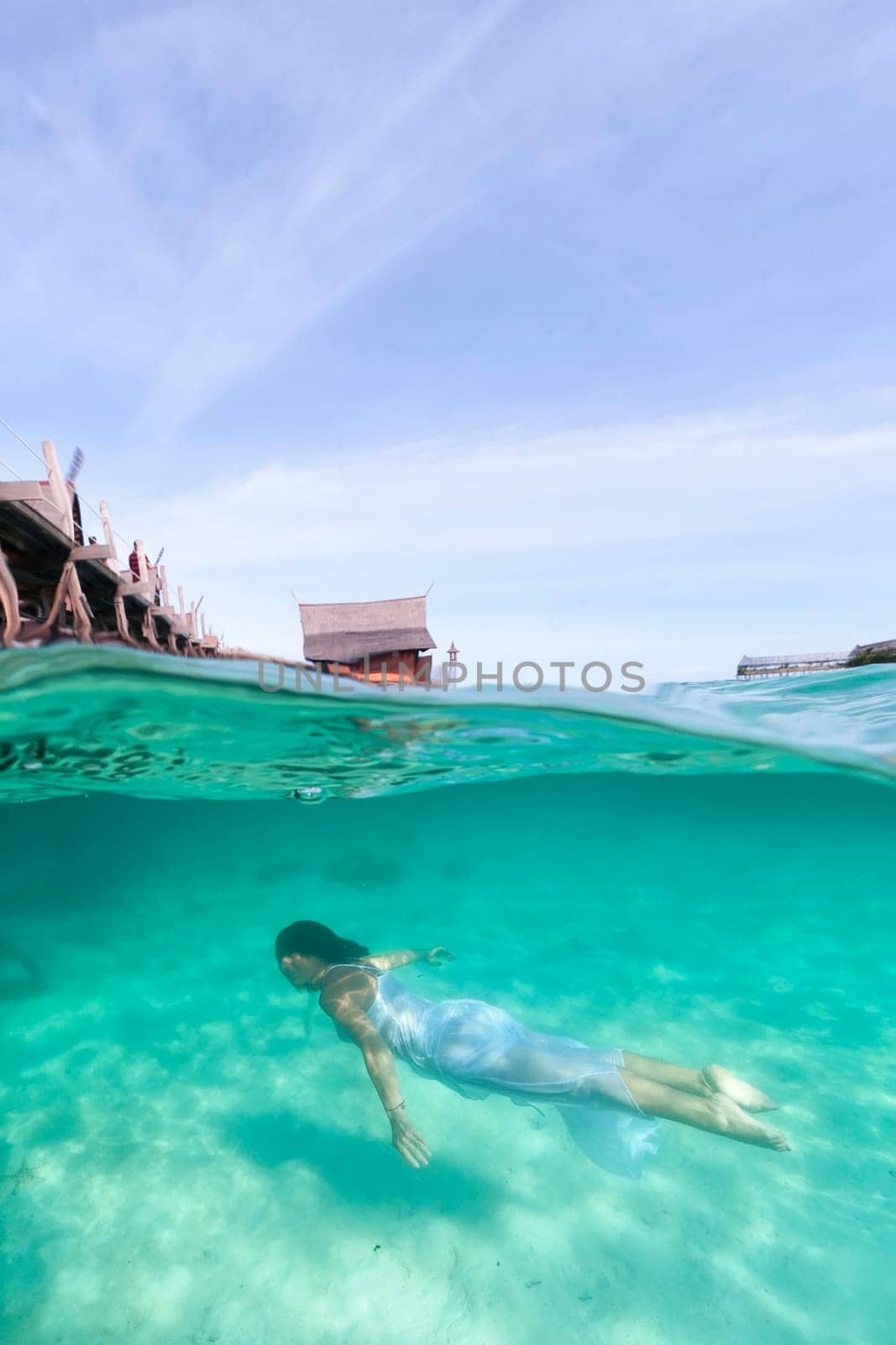 White dressed girl while swiming underwater in tropical turquoise paradise water