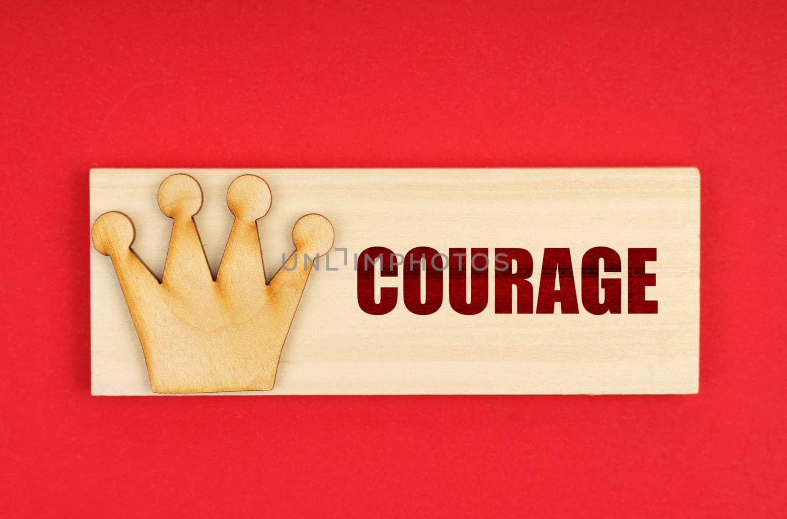 Leader concept. On a red surface there is a wooden block with the inscription - Courage
